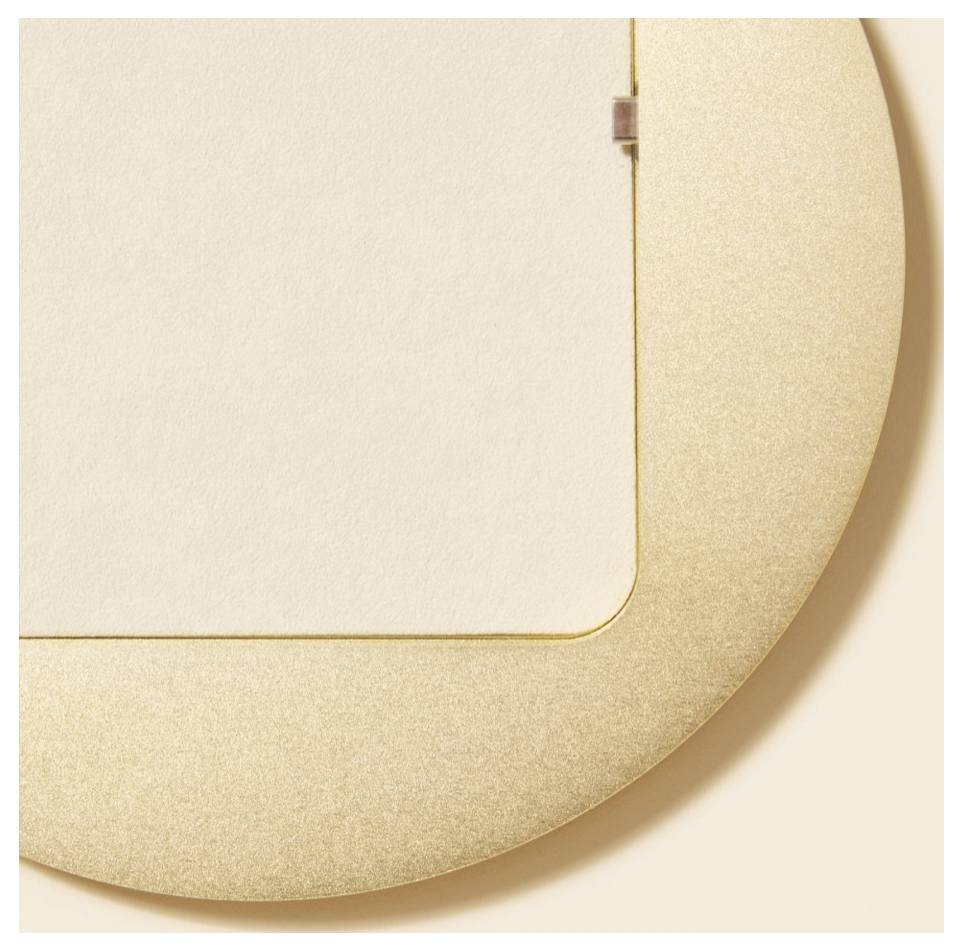 Nahaufnahme einer runden goldenen Bilderrahmenecke vor cremefarbenem Hintergrund, die ein minimalistisches Dekorationsobjekt zeigt.