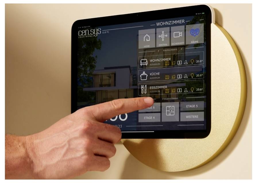 Hand zeigt auf ein Touchscreen-Bedienfeld zur Haussteuerung mit Räumen und Einstellungen in einer Smart-Home-Oberfläche.