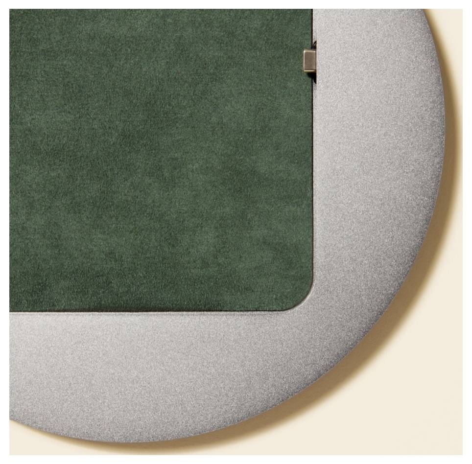 Nahaufnahme einer grauen Metalltür oder eines Metallpanels mit grünem Einsatz, die eine abgerundete Ecke und ein Scharnier vor einem beigefarbenen Hintergrund zeigt.