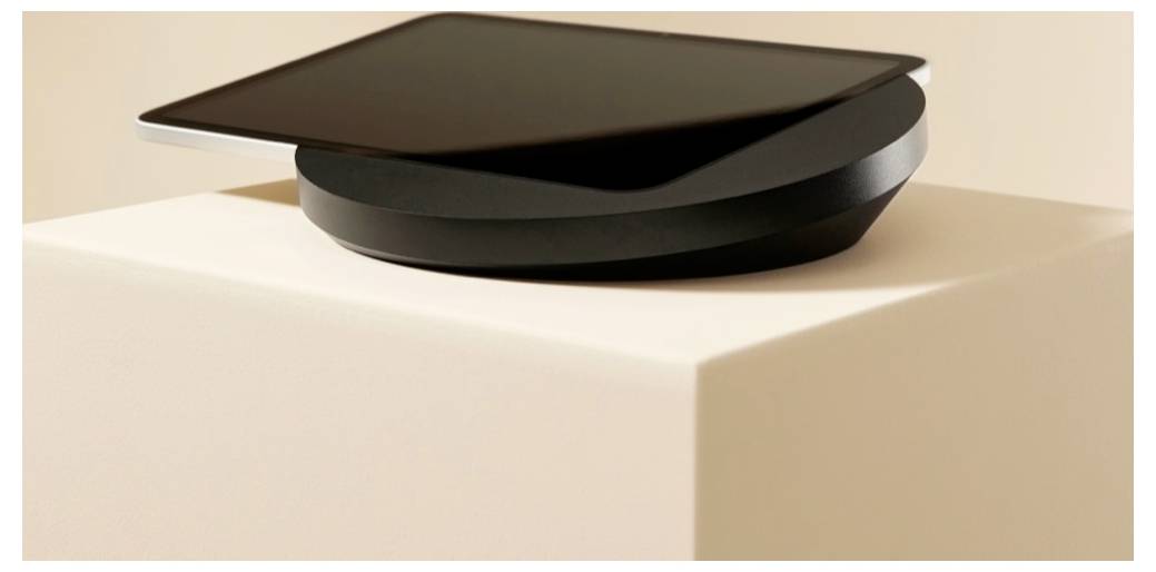 Eine elegante schwarze mehrschichtige Skulptur oder Schale sitzt auf einem beigen Sockel vor einem sanften neutralen Hintergrund.