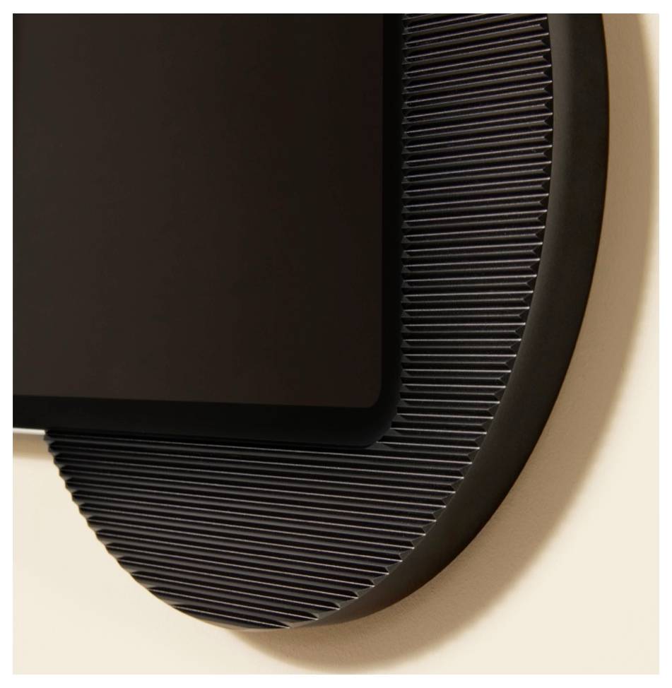 Nahaufnahme einer modernen schwarzen Wandleuchte mit gerillter Oberfläche, die ihr gekrümmtes kreisförmiges Design gegen eine beigefarbene Wand zeigt.