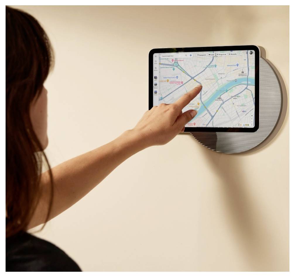 Frau berührt ein wandmontiertes Tablet, auf dem eine Navigationsapp mit einer Karte angezeigt wird.
