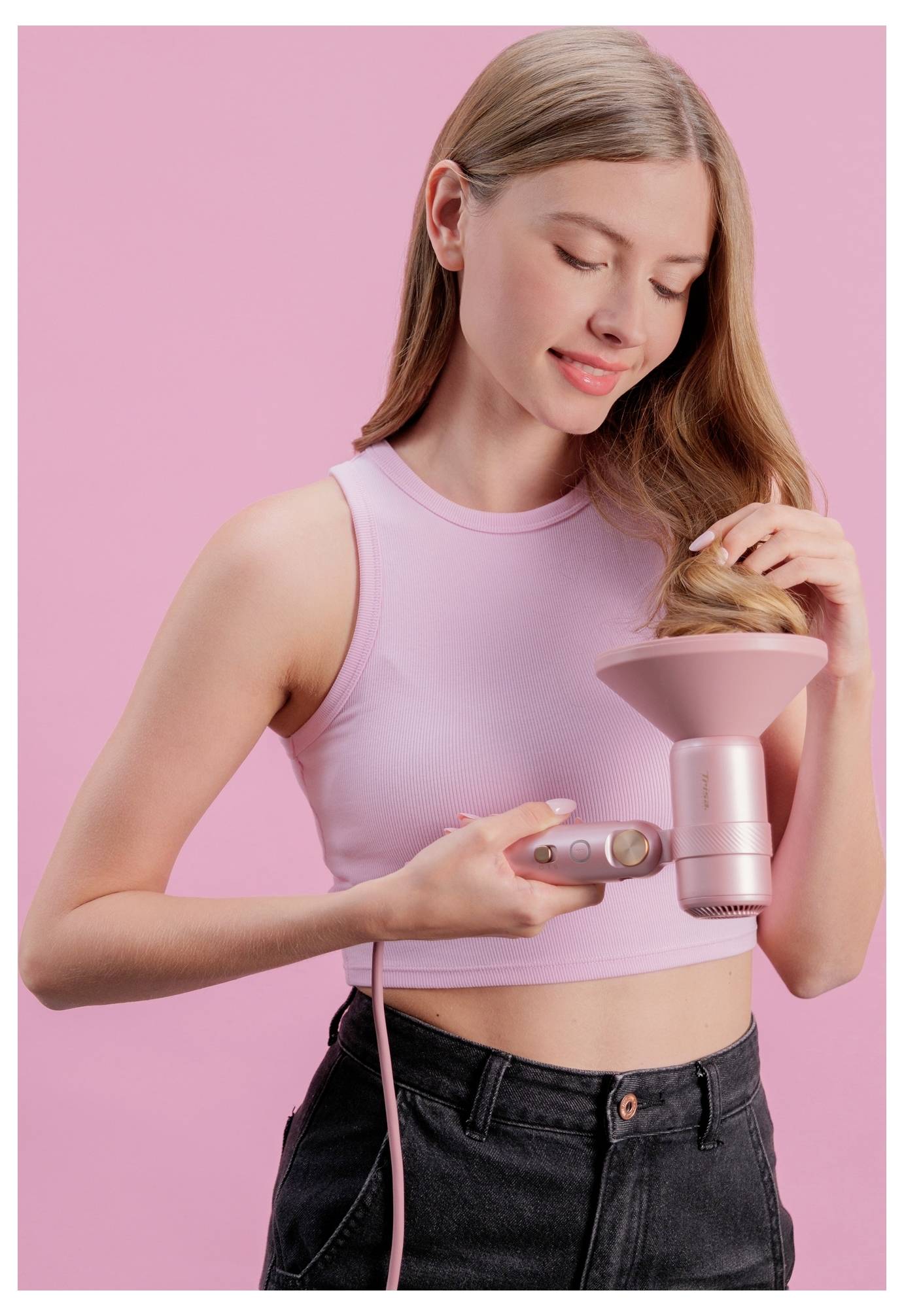 Junge Frau verwendet ein rosa Haarstyling-Gerät auf ihr Haar vor einem rosa Hintergrund.