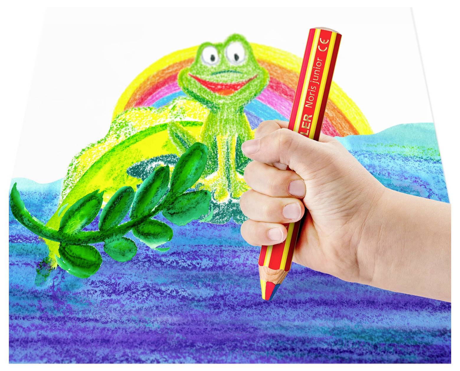 Eine Hand, die einen roten Buntstift hält, zeichnet einen grünen Frosch über blauem Wasser mit einem Regenbogen im Hintergrund.