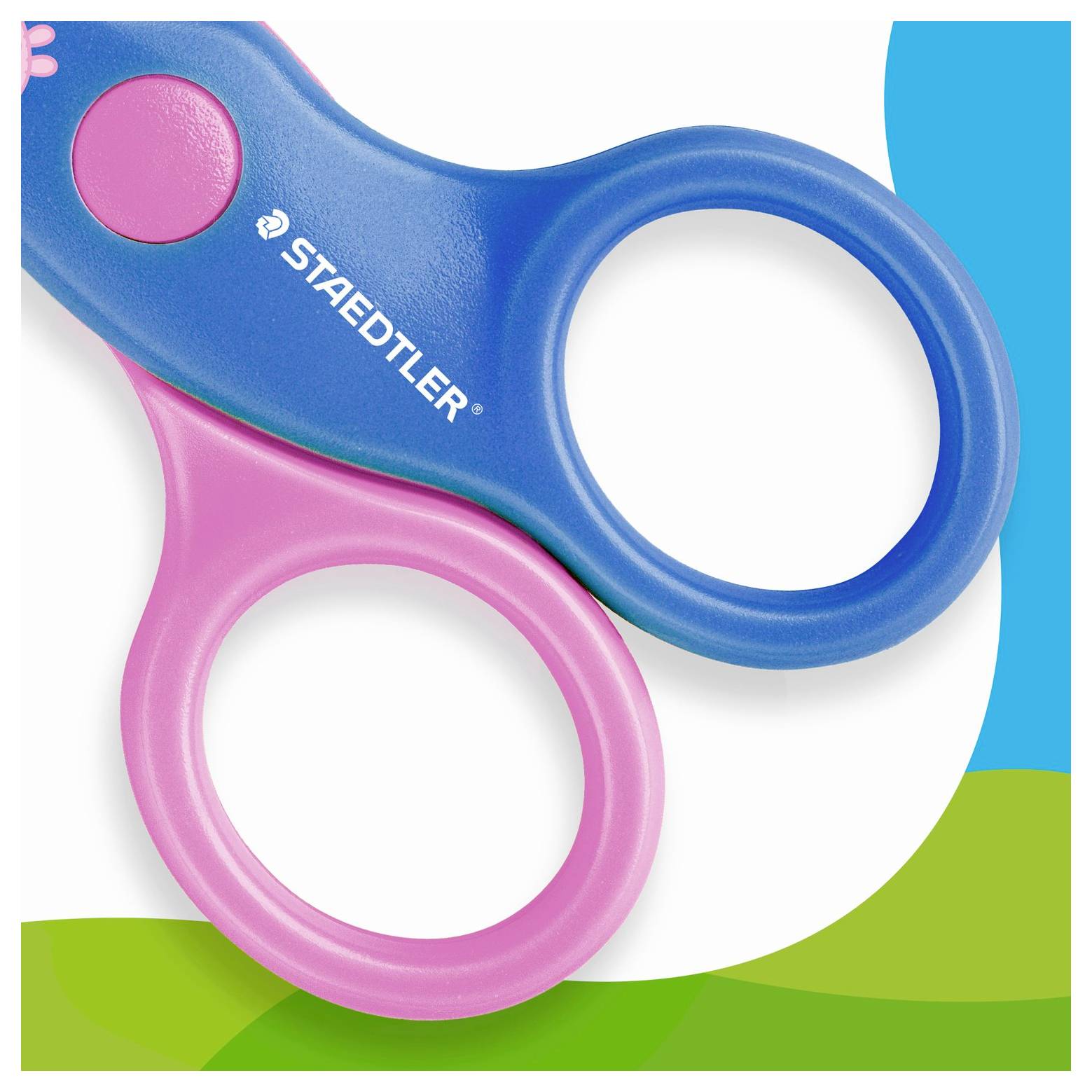 Blaue und rosafarbene STAEDTLER Kindersicherheitsscheren mit abgerundeten Fingerlöchern auf weißem Hintergrund mit grünen und blauen Akzenten.