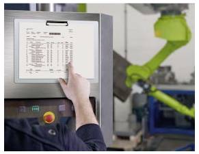 Ein Arbeiter bedient ein grünes Industrieroboter-Armgerät in einer Fabrik mit einem Touchscreen-Bedienfeld.