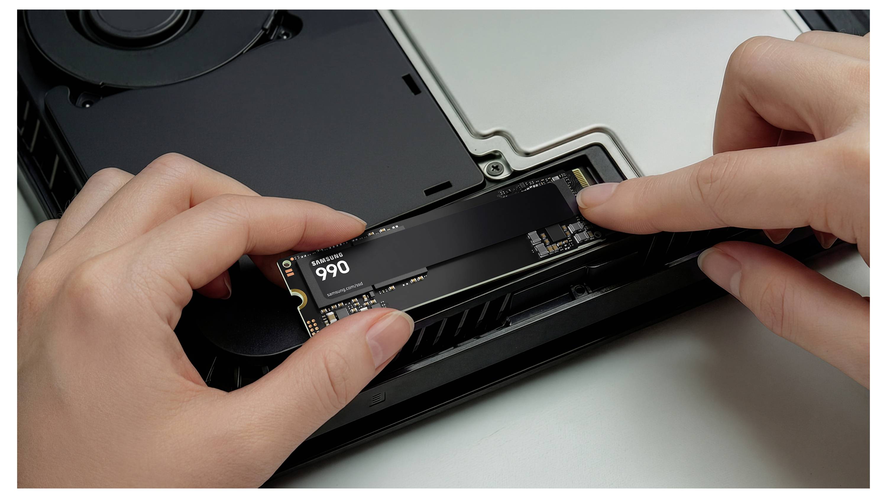 Hände, die eine M.2-NVMe-SSD in einen Computermotherboard-Steckplatz innerhalb eines Desktop-Gehäuses installieren.