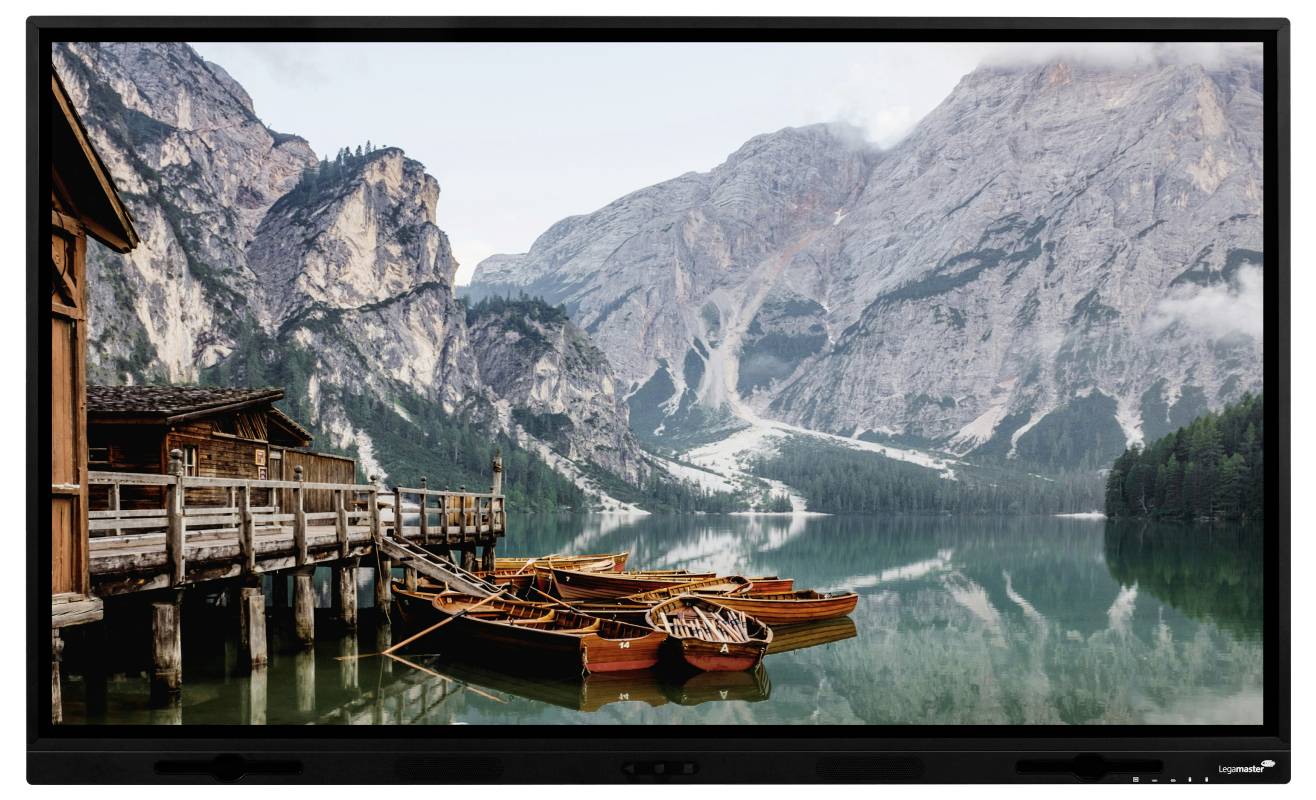 Ein Fernseher zeigt eine Bergseenlandschaft mit hölzernen Booten, die an einem Seesteg neben Klippen und Hütten festgemacht sind.