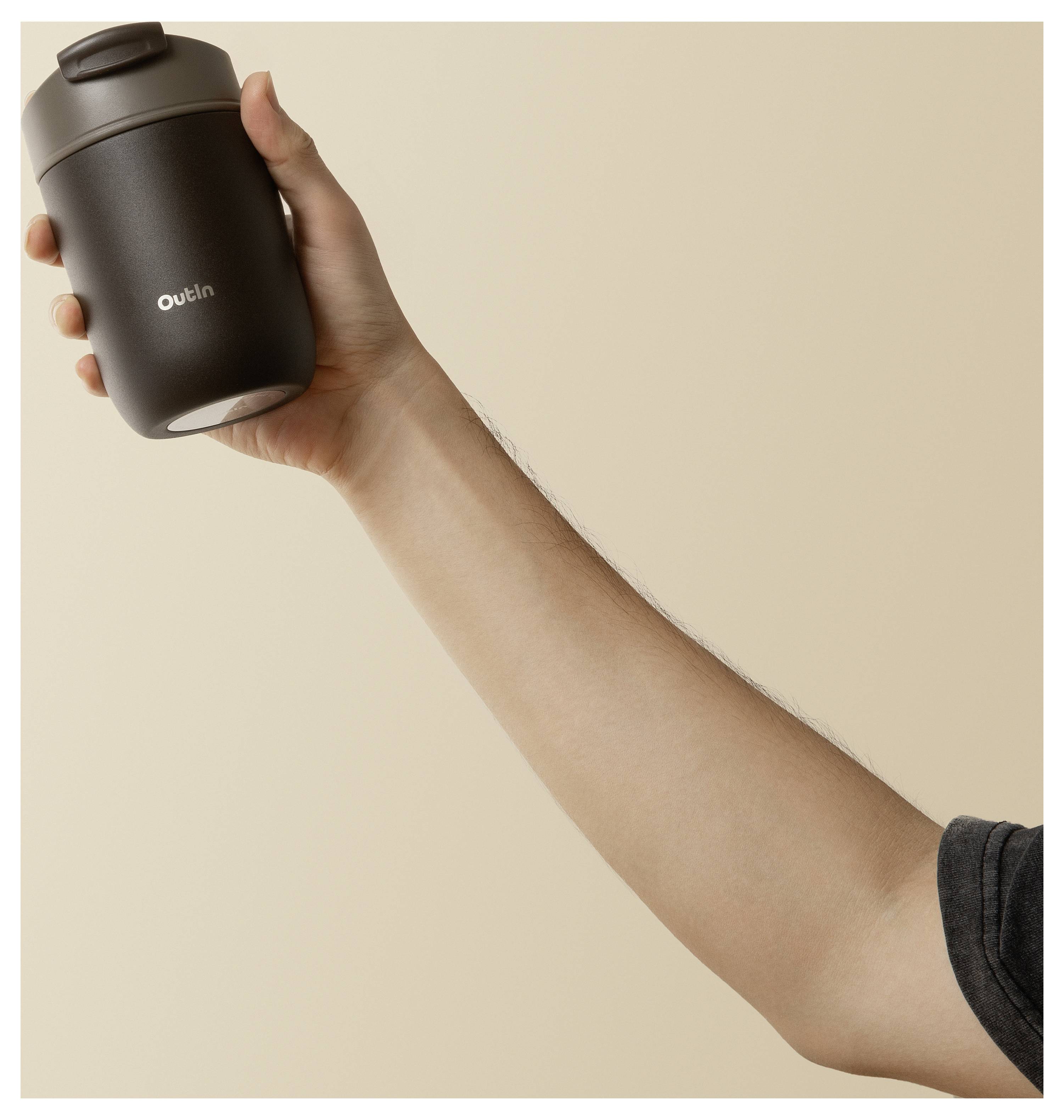 Hand hält eine matte schwarze Reiseta­sse mit dem Wort 