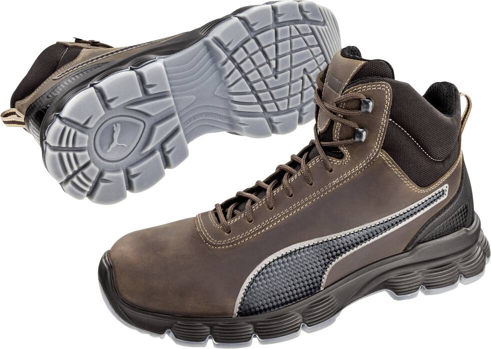 Paar braune Arbeitsstiefel, von der Seite und Sohle gezeigt, mit robustem schwarzem Profil und gepolsterter Knöchelunterstützung auf weißem Hintergrund.