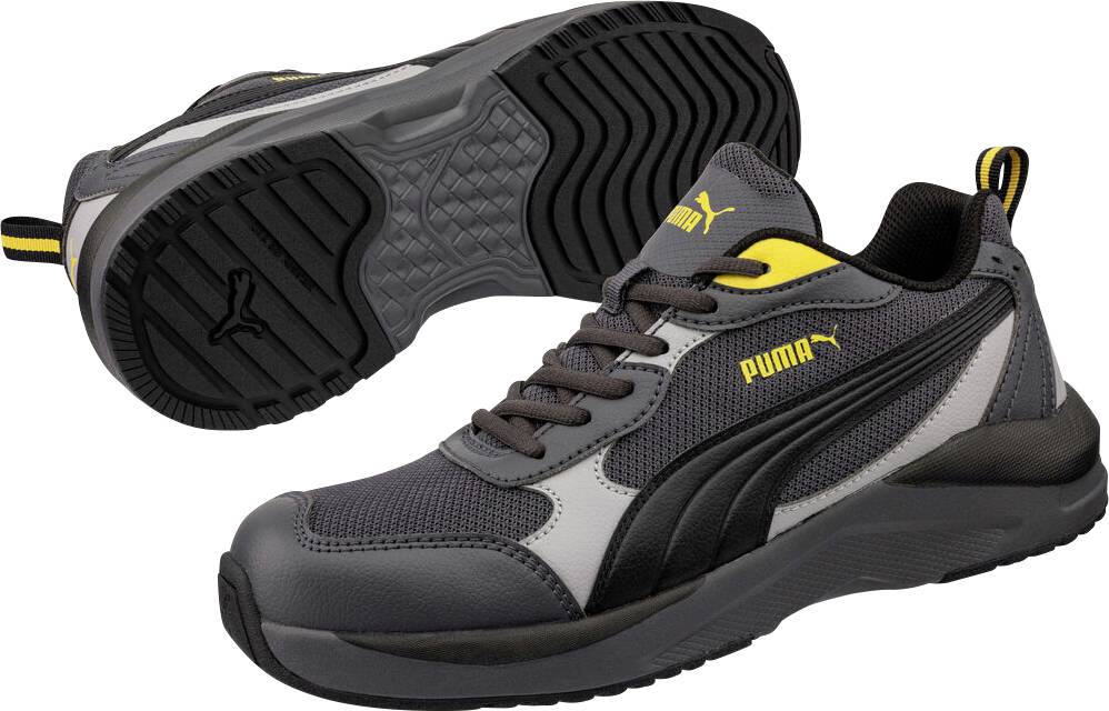 Graue und schwarze Puma-Sportschuhe von der Seite und Sohle gezeigt, mit gelben Logo-Akzenten und einer dicken Profilsohle.
