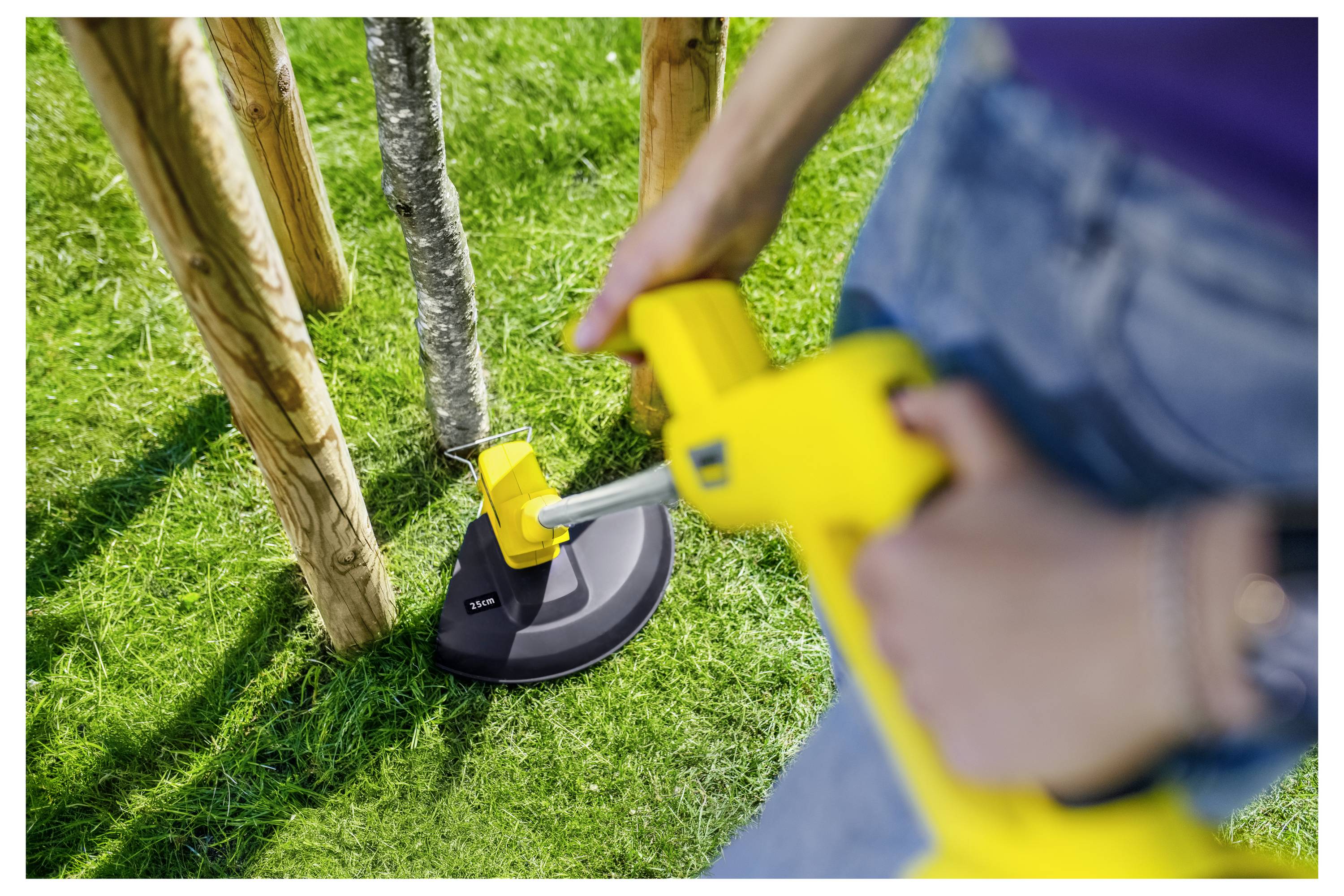 Person, der einen gelben elektrischen Trimmer verwendet, um Gras um Holzpfosten auf einem Rasen zu schneiden.