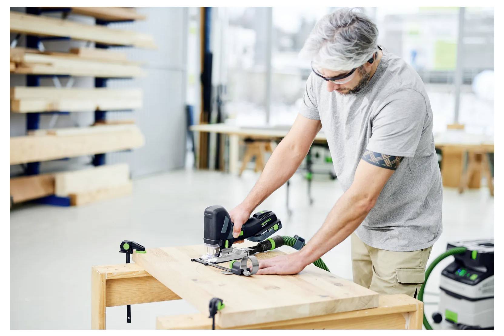 Ein Mann benutzt eine Stichsäge, um ein Holzbrett auf einer Werkbank in einer Werkstatt zu sägen.