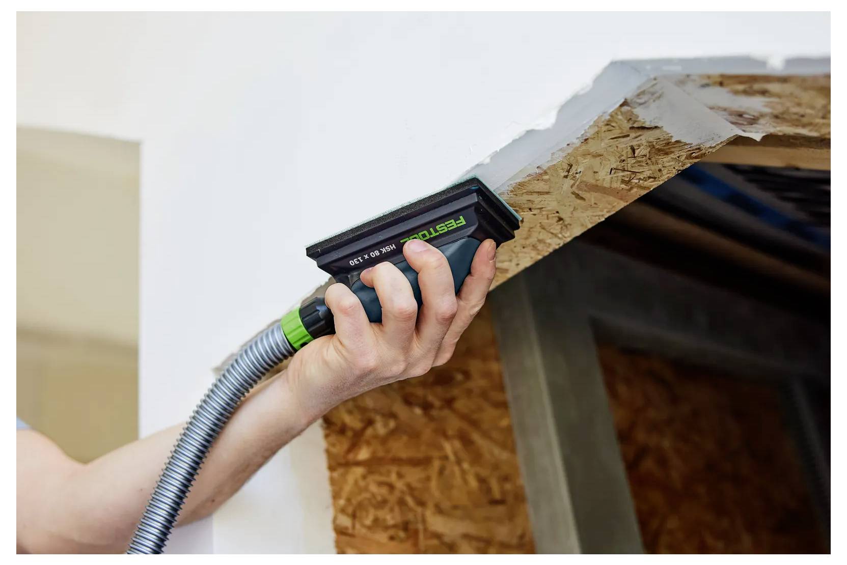 Ein Arbeiter verwendet ein tragbares Holzfeuchtemessgerät an einer Holzdachkante, um auf Wasserschäden oder Feuchtigkeit zu prüfen.