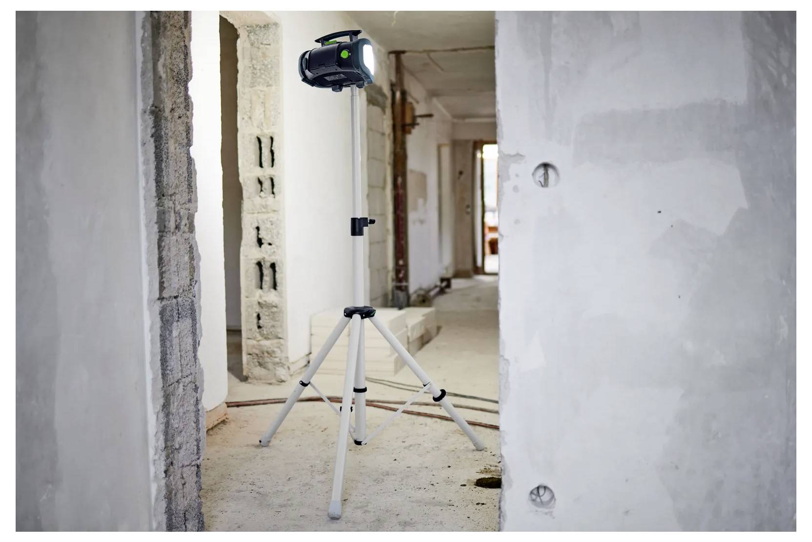 Laserlevel auf einem Stativ in einem unfertigen Innenflur unter Konstruktion.