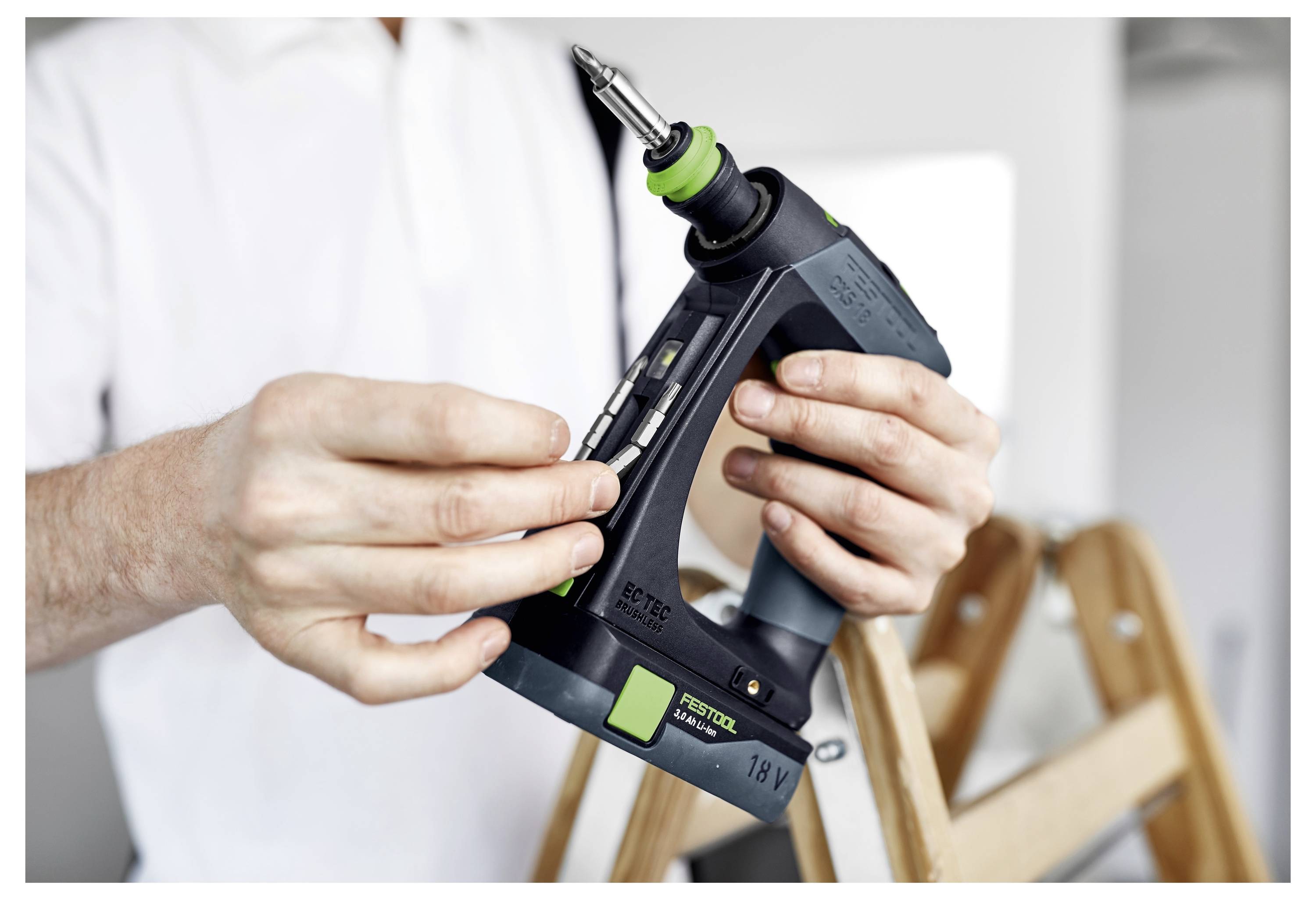 Eine Person hält eine kabellose Nagelschussmaschine und stellt den Nagelstreifen ein, um sie für die Verwendung in einer Heimreparatursituation vorzubereiten.