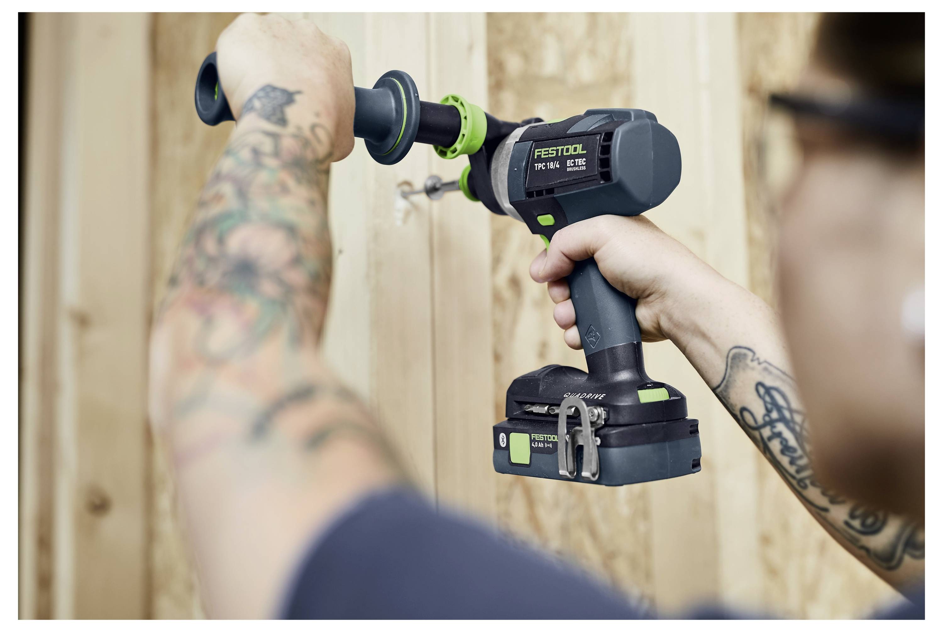 Person, die einen kabellosen FESTOOL-Bohrer mit einer Schleifaufsatz an einer Holzwandpaneele verwendet.