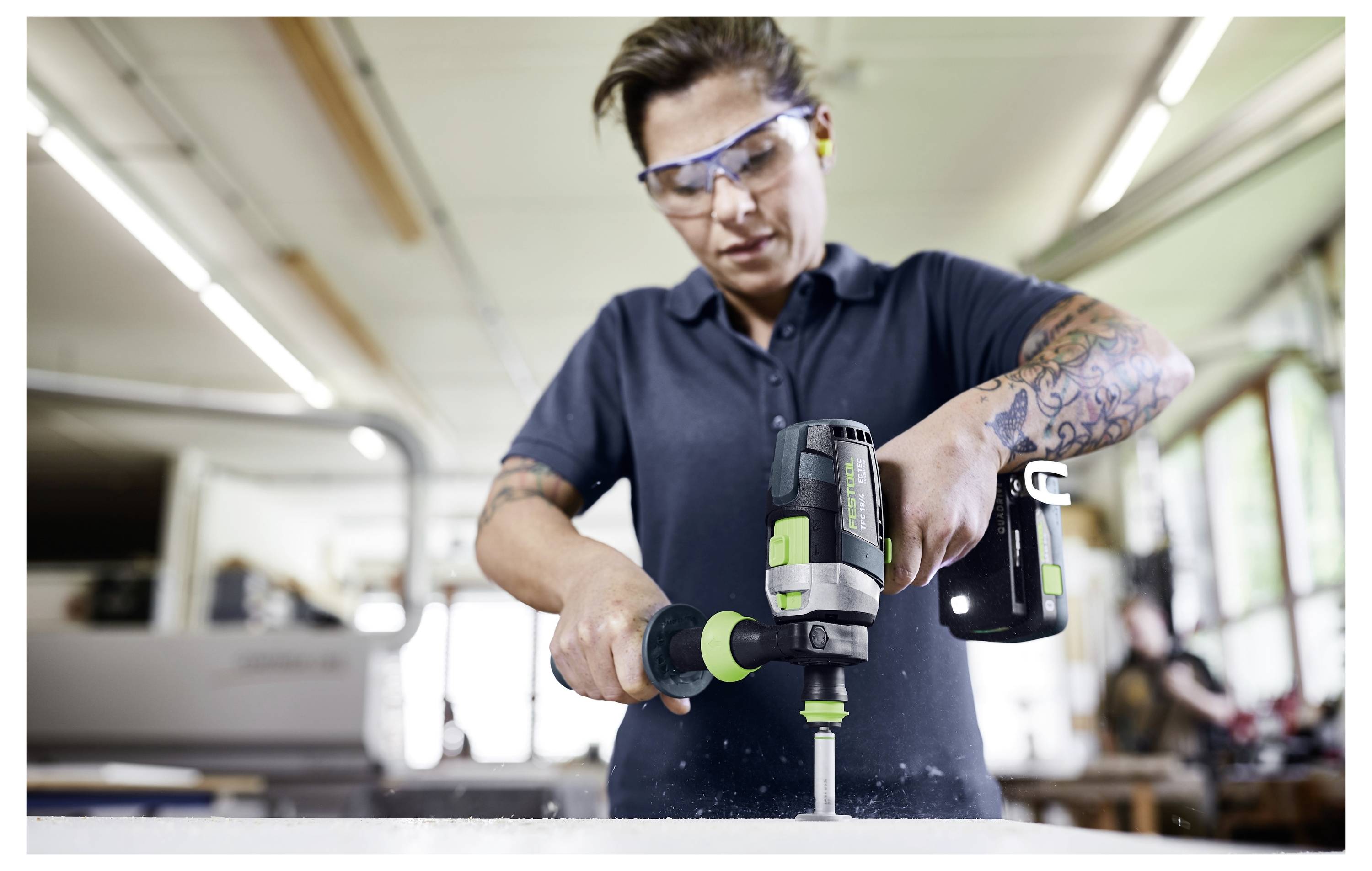 Ein Mann trägt eine Schutzbrille und benutzt einen kabellosen Bohrer, um an einem Projekt in einer Werkstatt zu arbeiten.