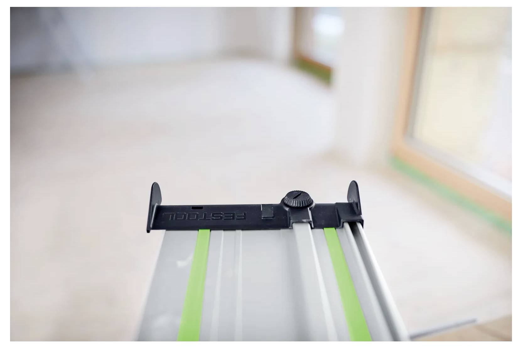 Nahaufnahme einer Festool-Führungsschiene für Tauchsägen mit grünen Streifen, fotografiert in einem hell beleuchteten Renovierungsraum.
