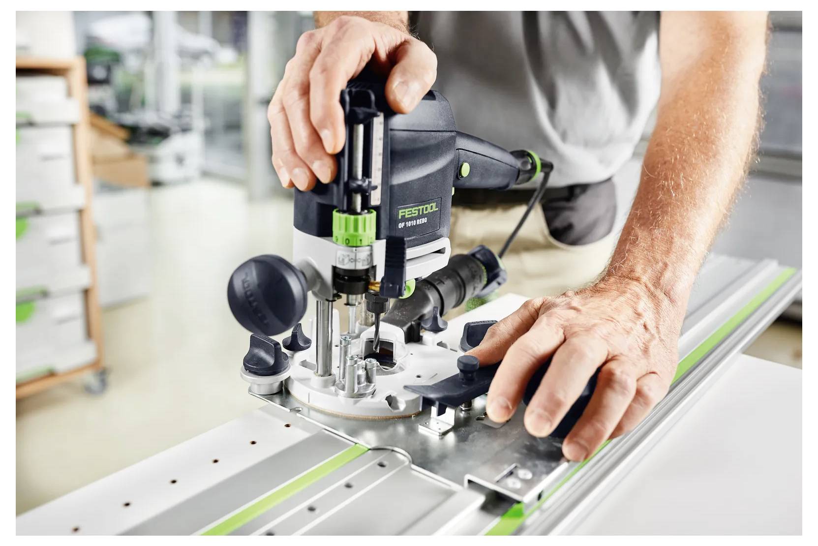 Person, die einen Festool-Fräser auf einer Werkbank benutzt, das Werkzeug mit beiden Händen führt, um Material zu schneiden oder zu formen.