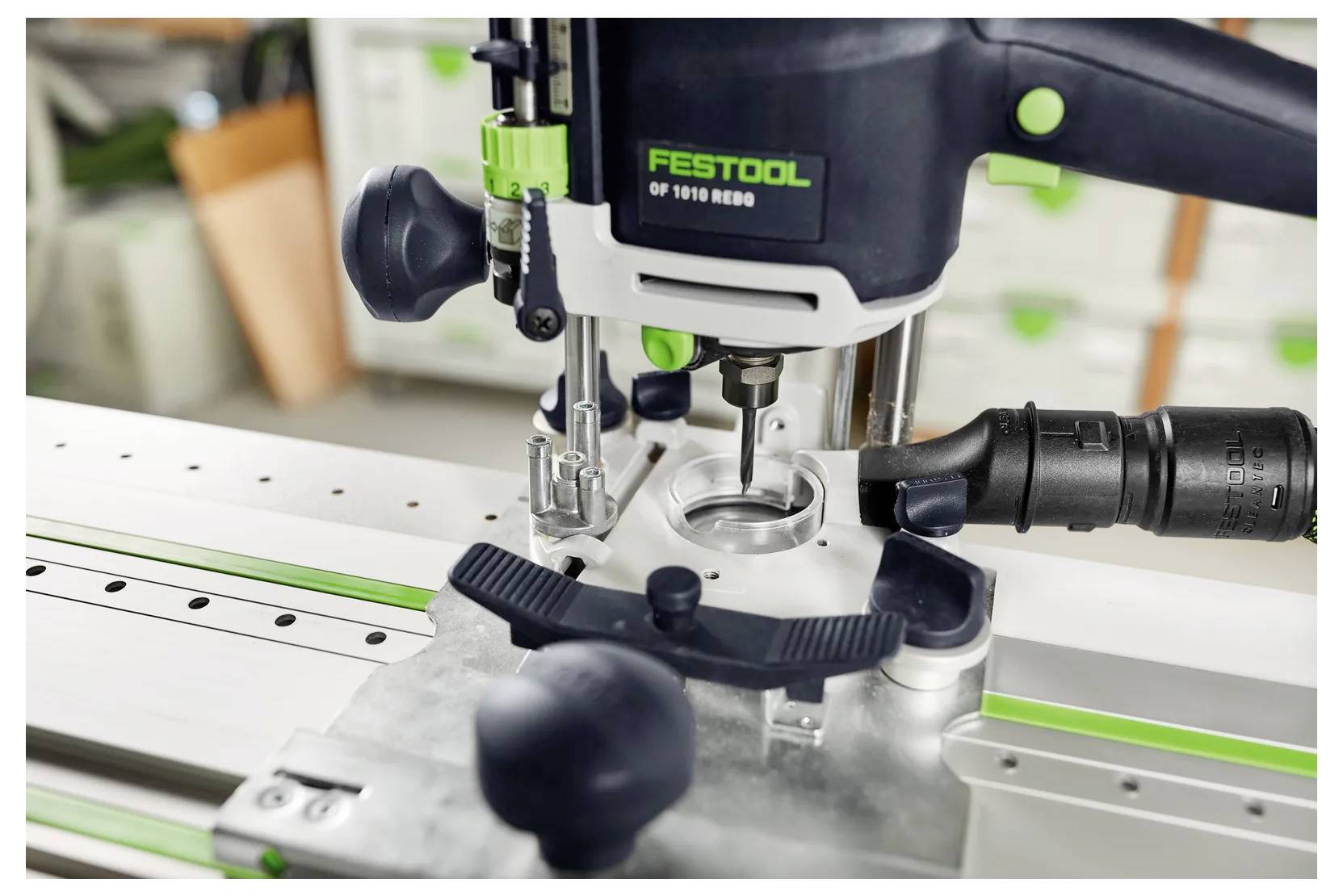 Ein Festool-Tauchrouter, der mit Hilfe einer geführten Schiene eine kreisförmige Vertiefung in ein Werkstück schneidet, gezeigt in einer Werkstatt.