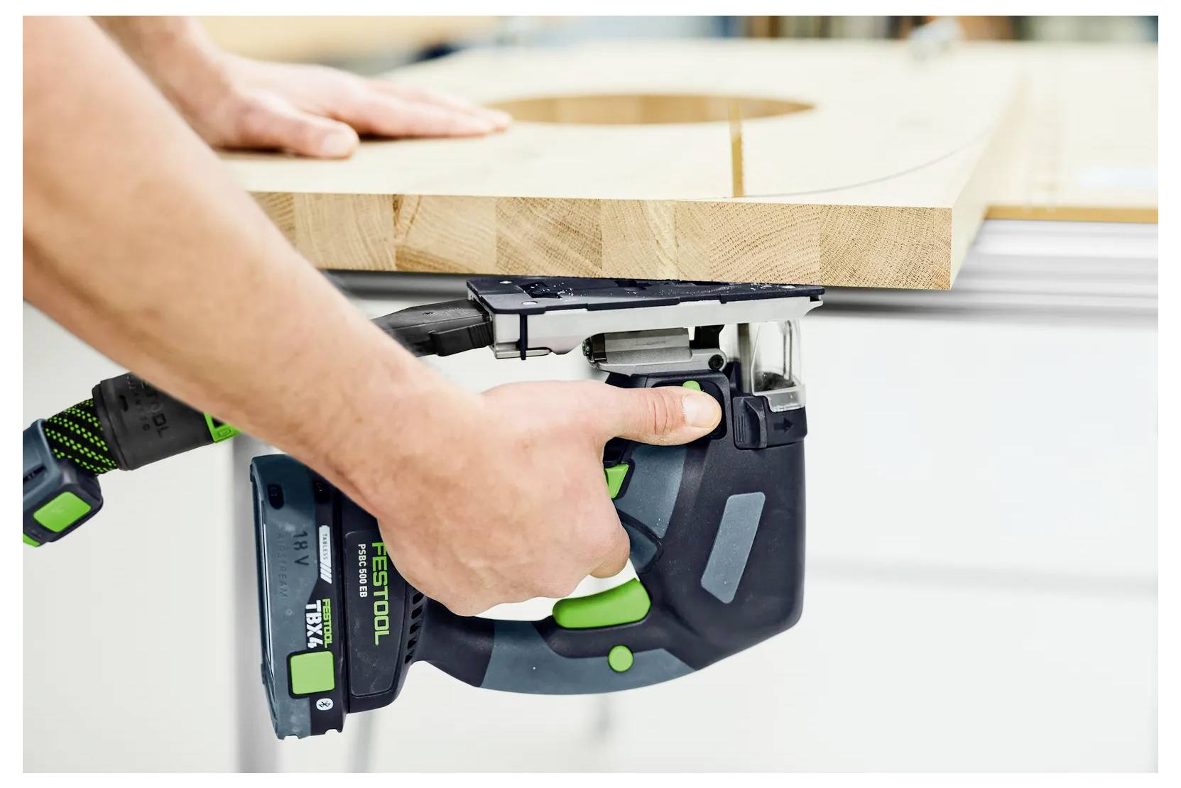 Person, die mit einer Festool-Elektrohandkreissäge die Kante eines Holzbretts auf einer Werkbank schneidet