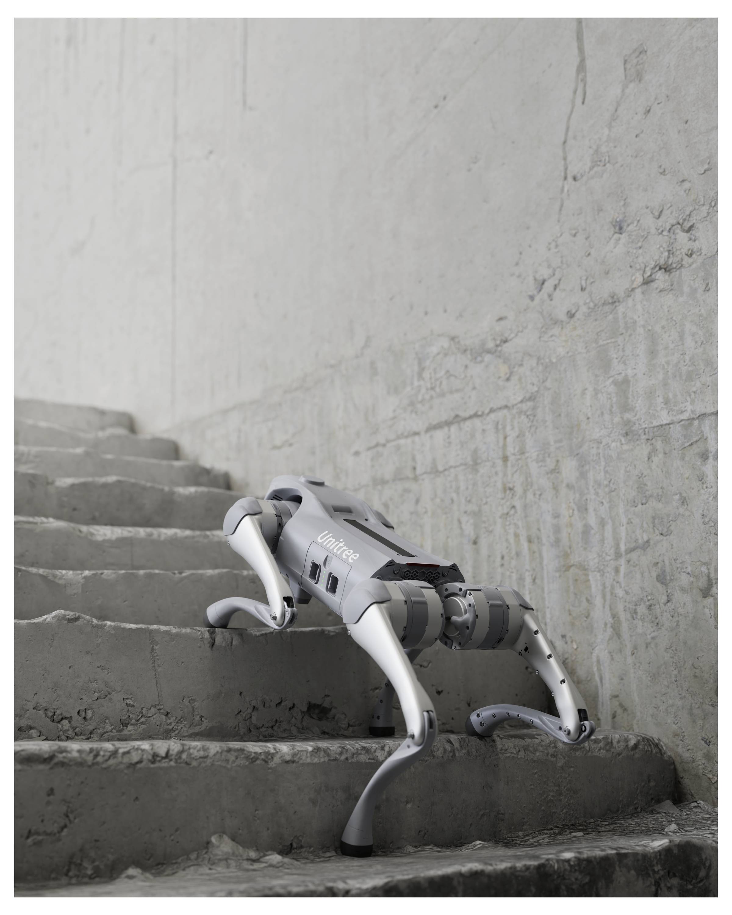 Ein robotisches vierbeiniges Gerät erklimmt raue Betontreppen neben einer rissigen Wand in einem unfertigen Innenraum.