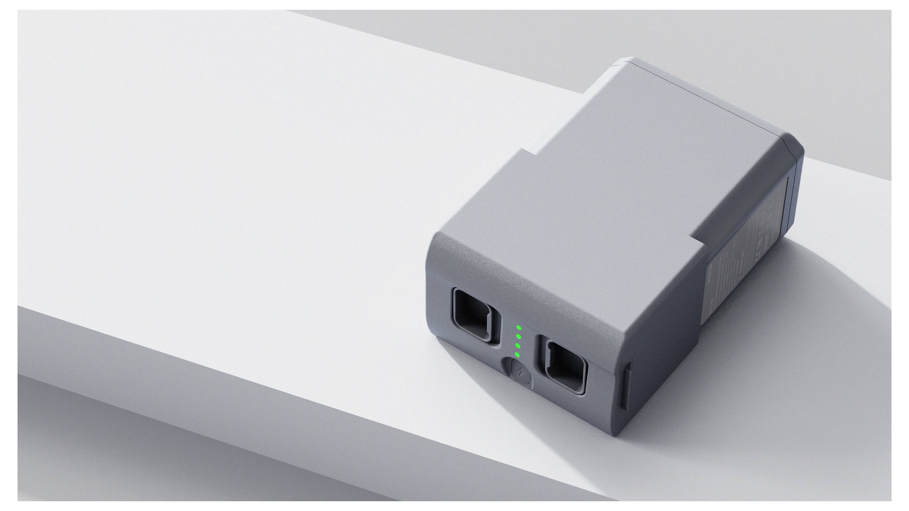Kleines graues elektronisches Akkupack oder Netzteil mit zwei USB-Anschlüssen und grünen LED-Indikatoren auf einer weißen Oberfläche.