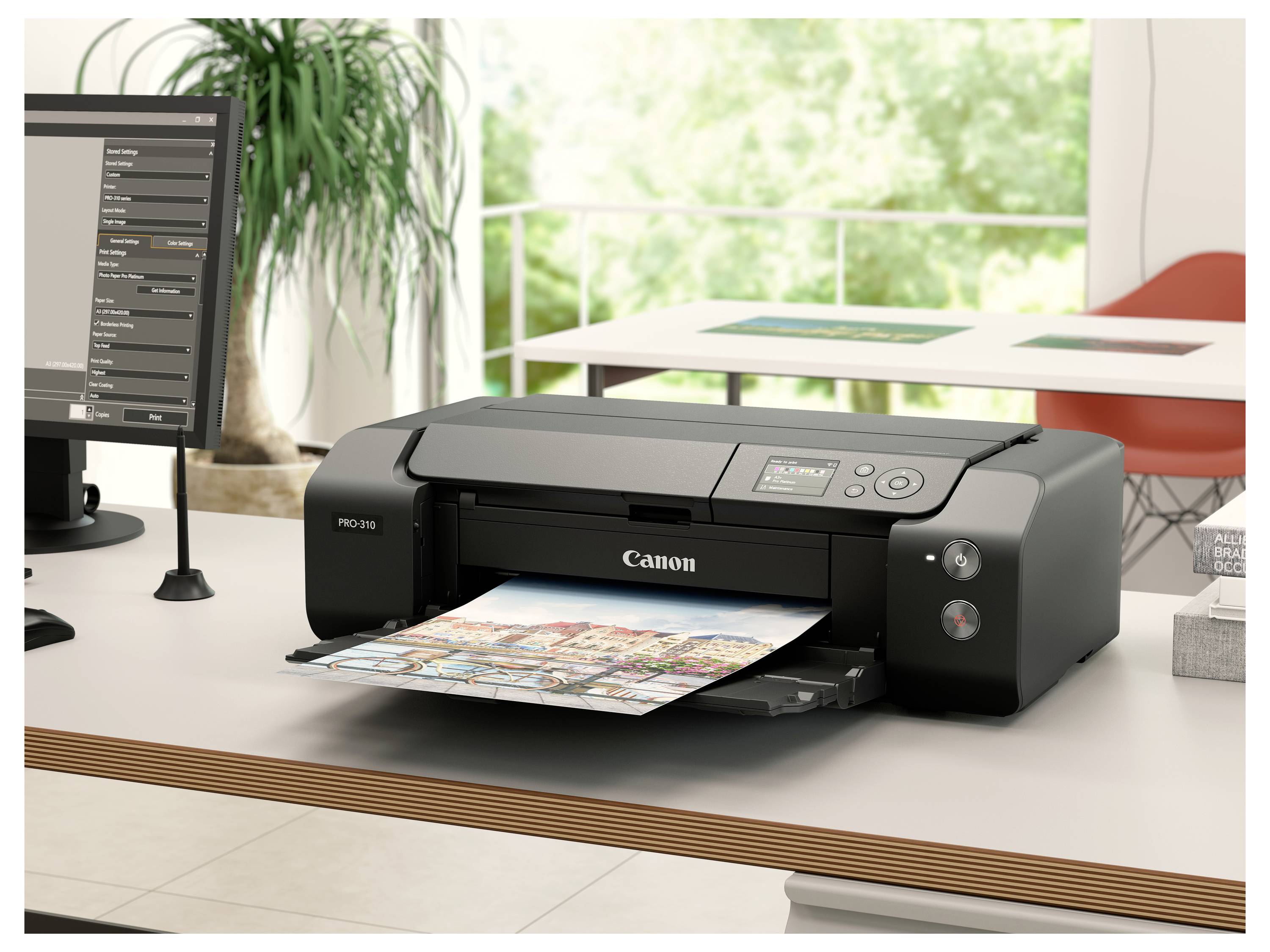 Ein Canon-Fotodrucker druckt ein buntes Blatt auf einem Schreibtisch neben einem Computermonitor in einem hellen Homeoffice.