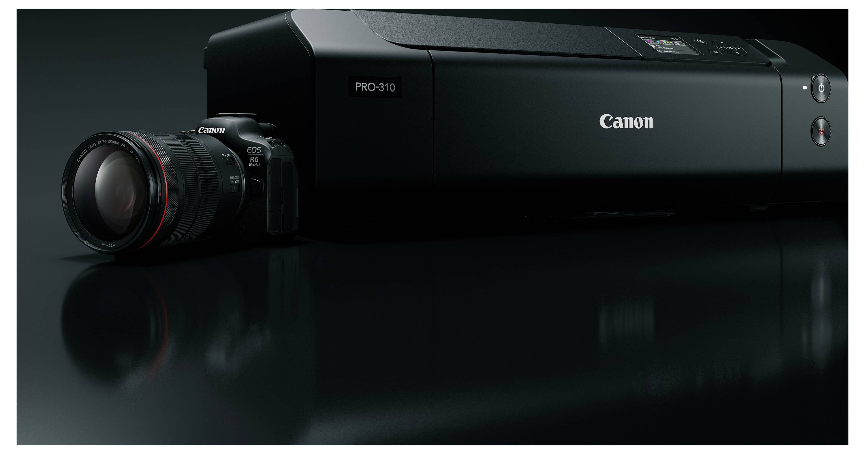 Canon PRO-310 Drucker neben einem Canon-Kameraobjektiv, gezeigt in einem dunkelstudio-ähnlichen Produktbild mit glänzender Spiegelung.