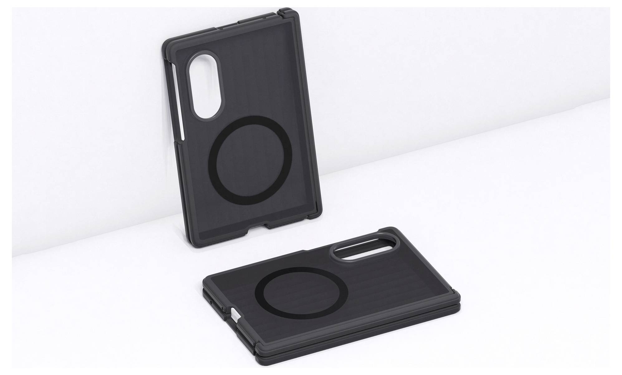 Zwei schwarze Smartphone-Hüllen mit kreisförmigen MagSafe-ähnlichen Ringen, eine aufrecht stehend und eine flach auf einer weißen Oberfläche liegend.