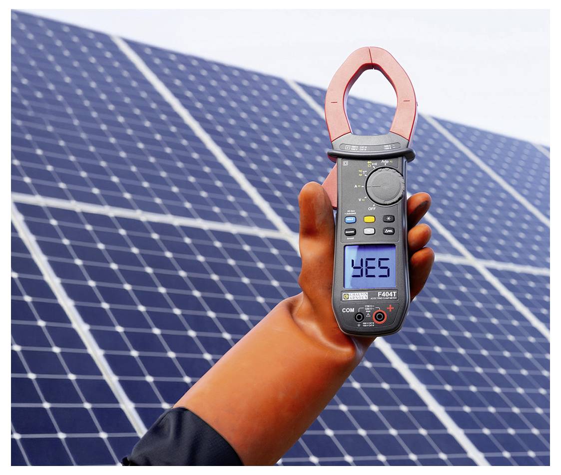 Hand, die ein digitales Zangenprüfgerät vor Solarpaneelen hält, wobei das Display 