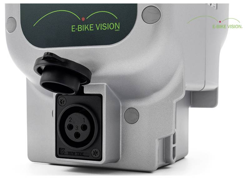 Nahaufnahme eines silbernen E-BIKE VISION-Batterie-Steckerports mit schwarzer Gummikappe und Logo auf dem Gehäuse.
