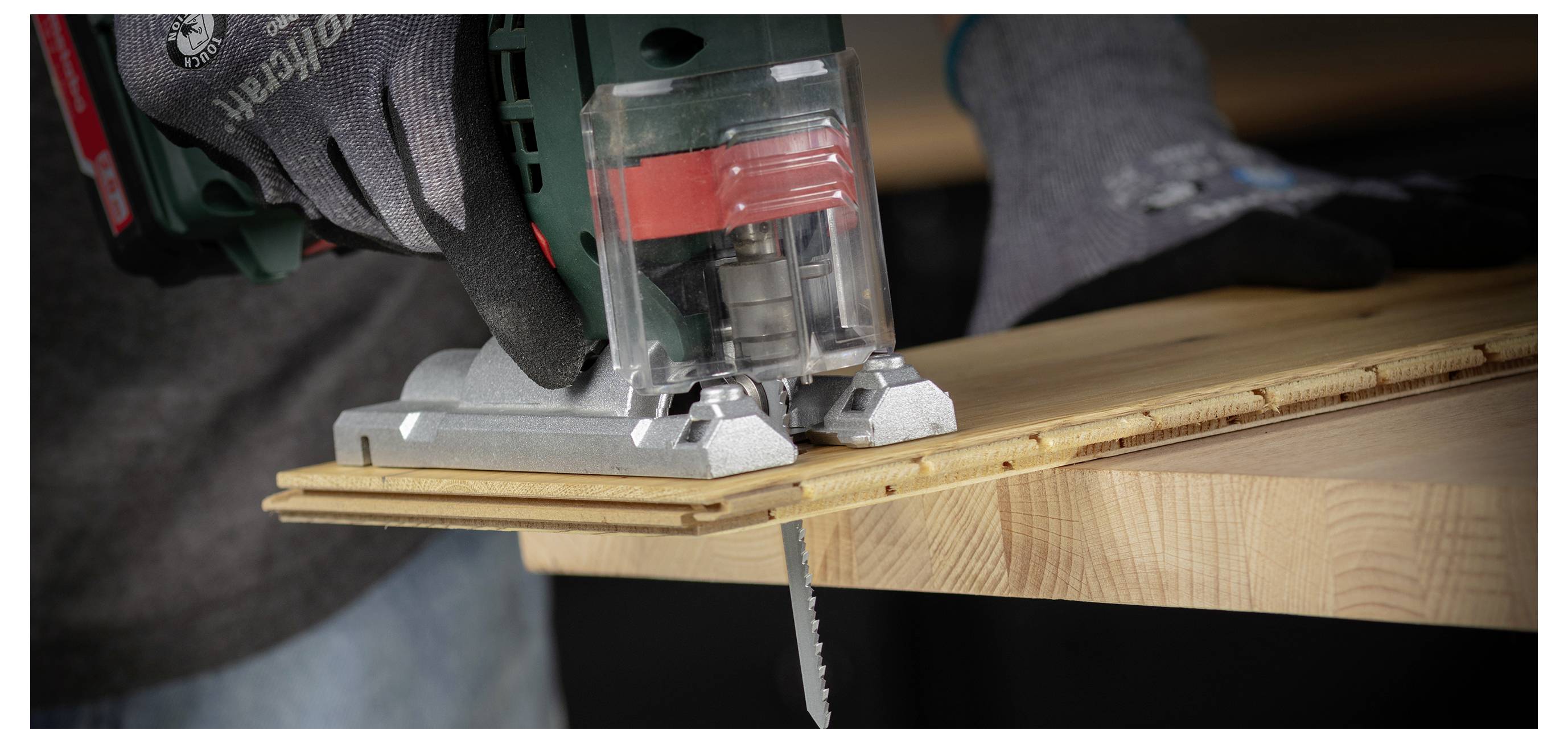 Nahaufnahme einer Stichsäge, die ein Holzbrett auf einer Werkbank schneidet.
