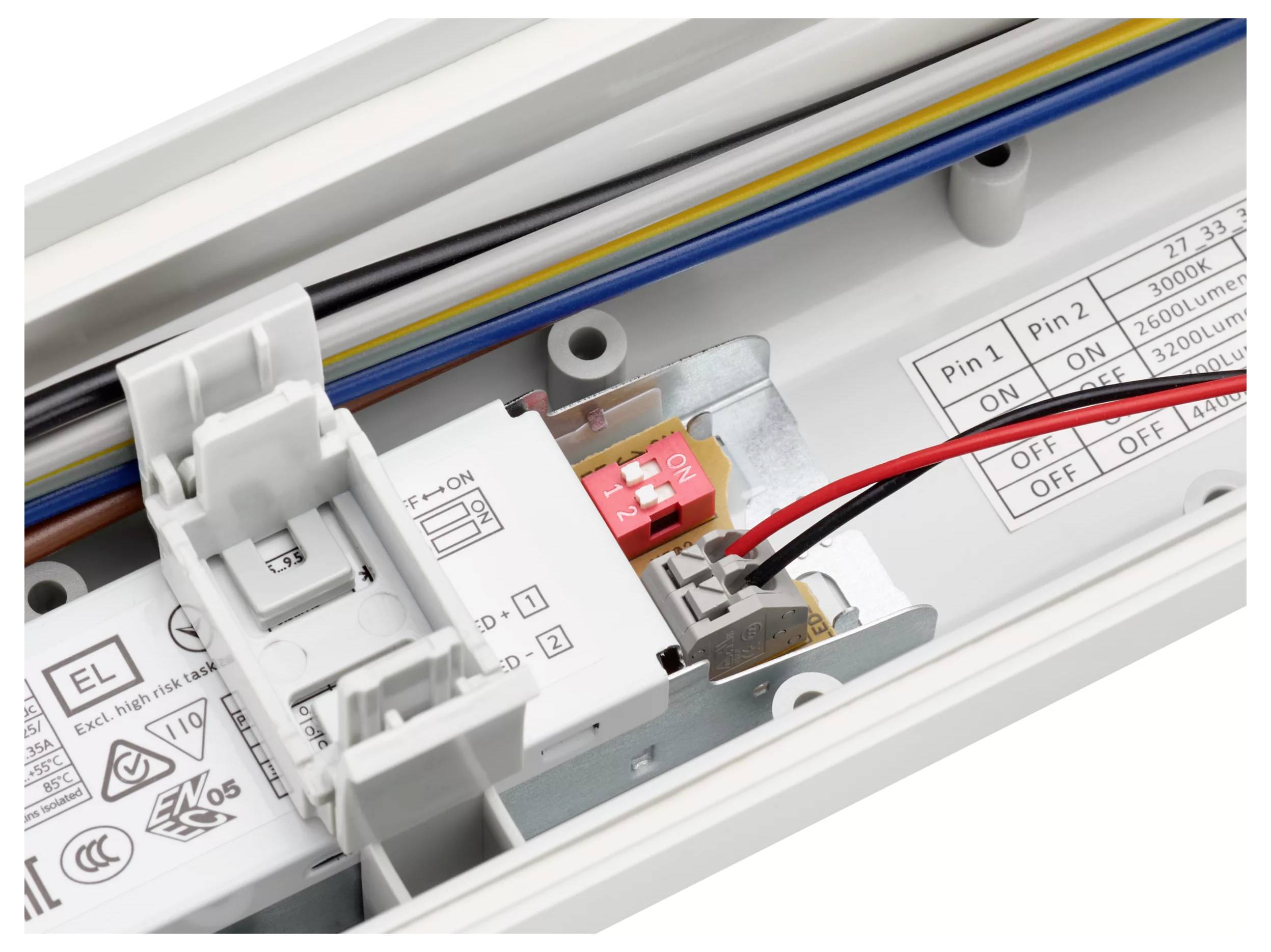 Nahaufnahme eines Bedienfelds eines elektrischen Geräts mit einem roten Ein-/Ausschalter, verbundenen Drähten und gedruckten Schaltungen sowie Einstellungsbeschriftungen.