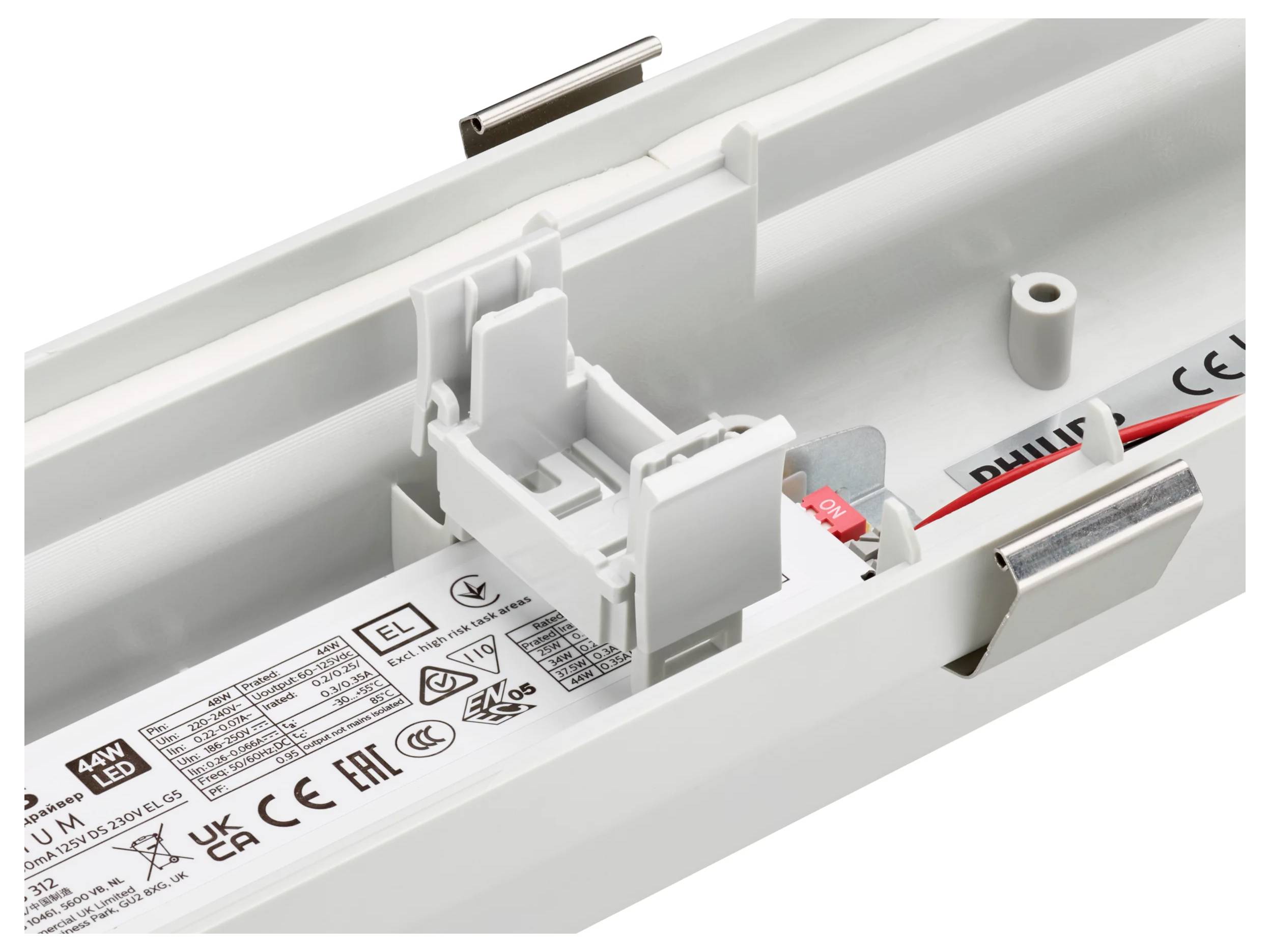 Nahaufnahme des Inneren einer weißen LED-Leuchte mit Verdrahtungsraum, Stecker und Produktetikett.