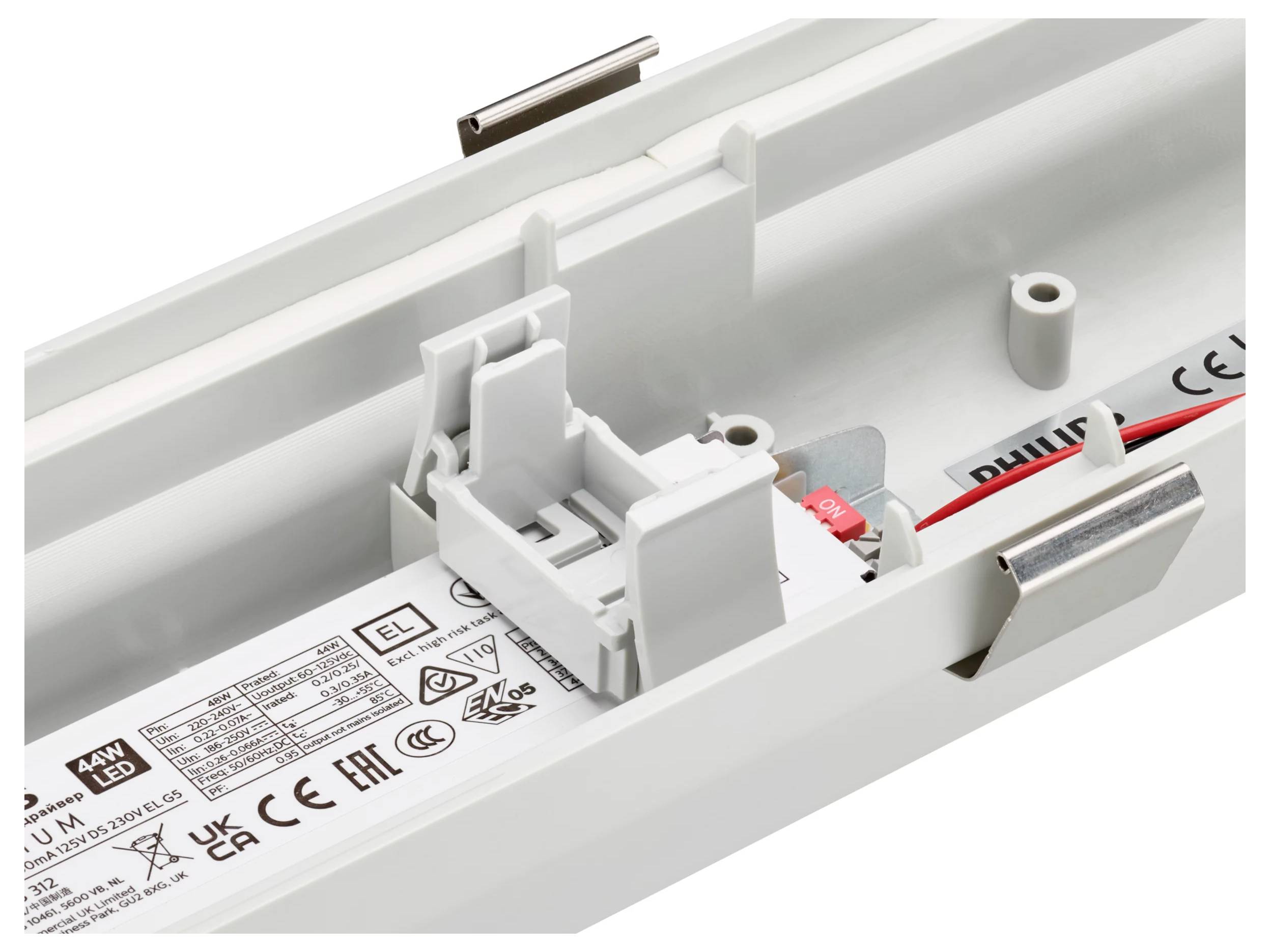 Nahaufnahme einer weißen LED-Leuchte mit sichtbarer interner Verdrahtung, Befestigungsclips und einem beschrifteten elektronischen Treibermodul.