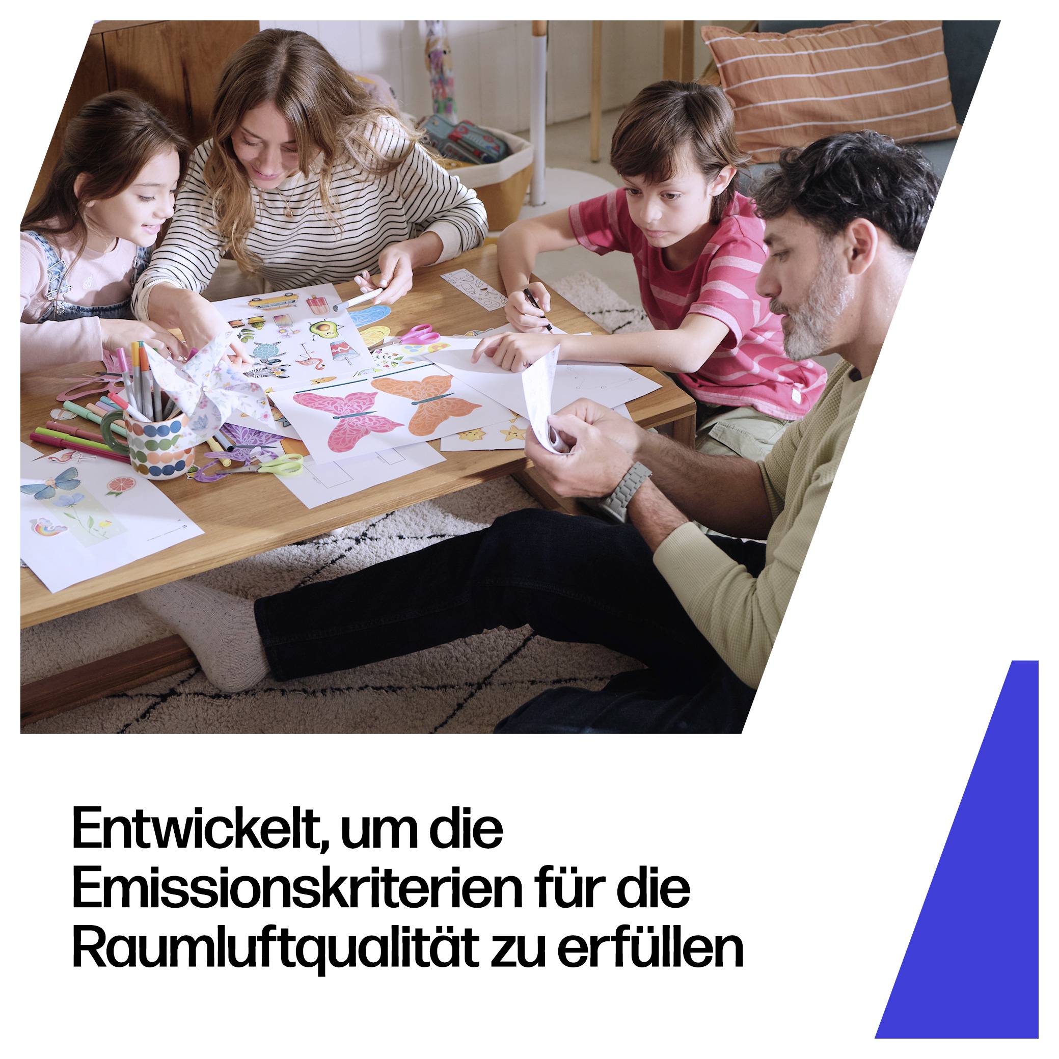 Familie zu viert, die an einem Tisch Papierhandwerk macht, darunter deutscher Text, der lautet „Entwickelt, um die Emissionskriterien für die Raumluftqualität zu erfüllen