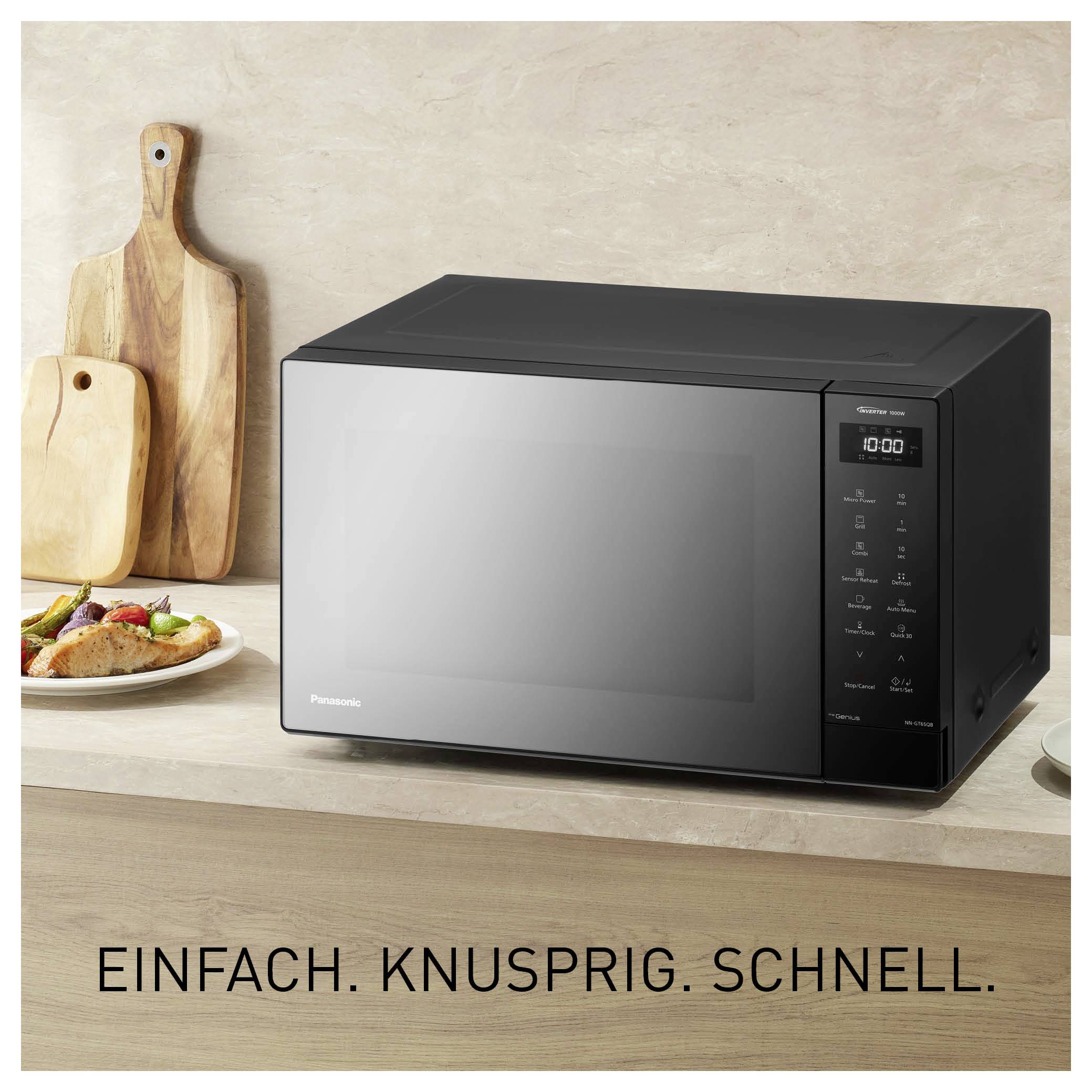 Schwarzer Panasonic-Mikrowellenofen auf einer Küchenarbeitsplatte mit Brot und Schneidebrettern; unten steht 'EINFACH. KNUSPRIG. SCHNELL.'
