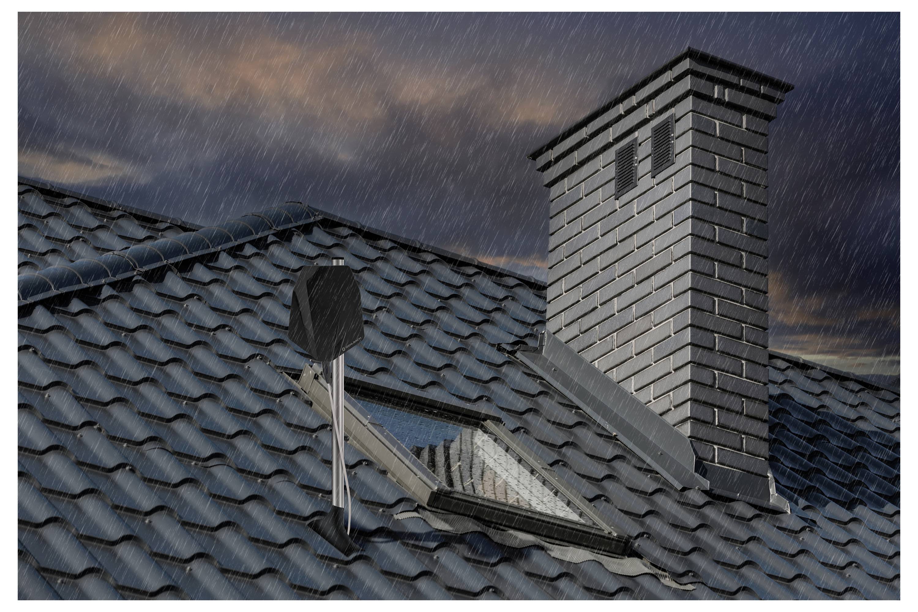 Regen fällt auf ein dunkles Ziegeldach mit einem Ziegelschornstein und einem Dachfenster unter einem bewölkten Abendhimmel.