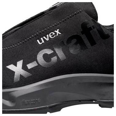 Nahaufnahme eines schwarzen Uvex x-craft Sicherheitsschuh-Obermaterials mit großem silbernem Branding und sichtbaren Nähten auf der Seite.
