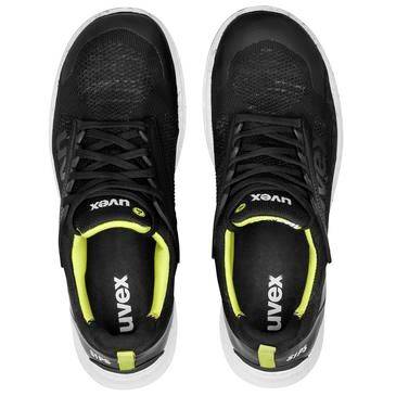 Draufsicht auf zwei schwarze Sportschuhe mit neongrünen Akzenten und weißen Sohlen, nebeneinander auf weißem Hintergrund abgebildet.