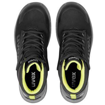 Draufsicht auf ein Paar schwarzer Uvex-Sportschuhe mit neongelber Innenfütterung und grauen Sohlen auf weißem Hintergrund.