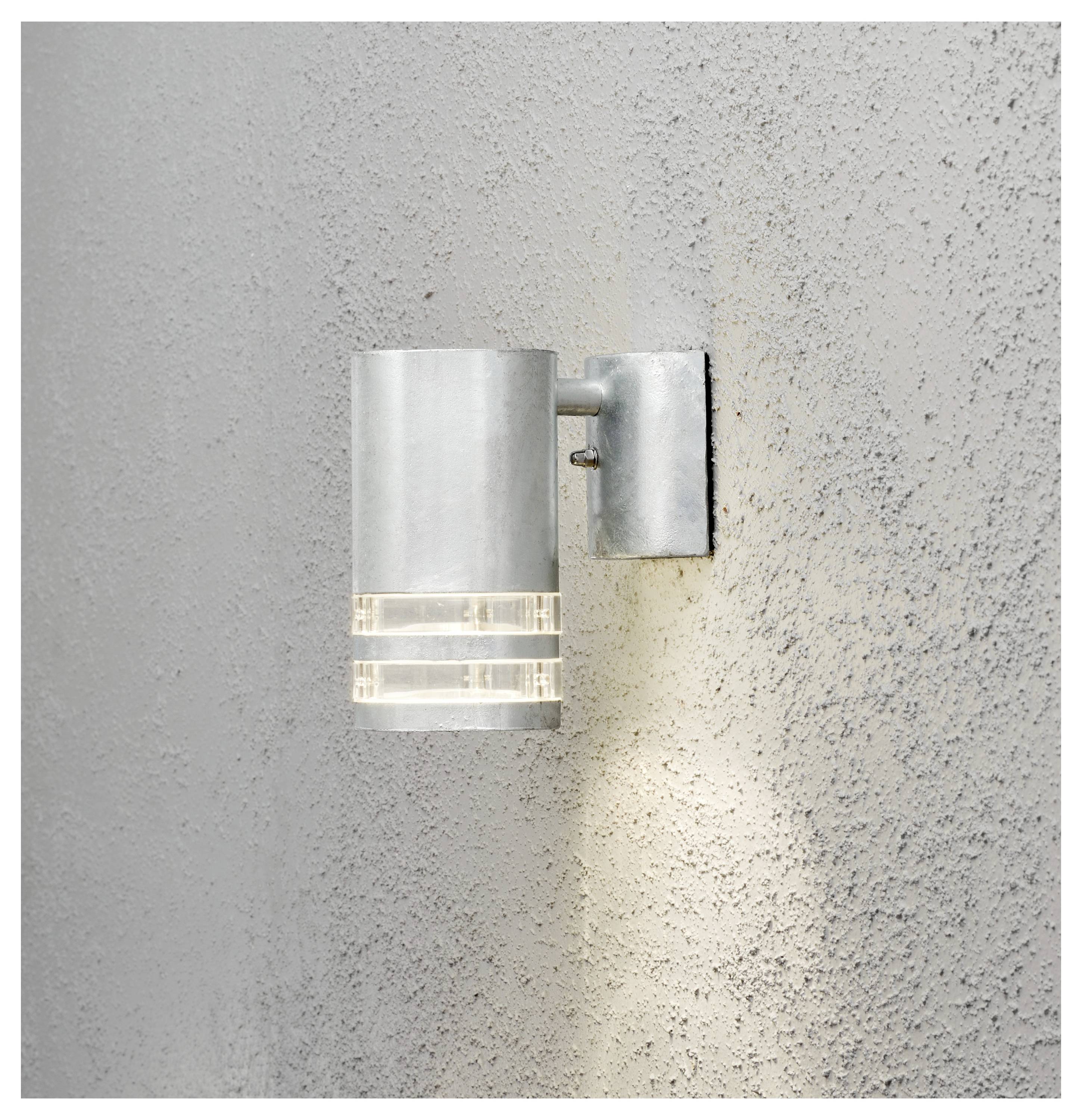 Moderne Wandleuchte mit mattiertem Glasschirm, die ein warmes Licht nach unten auf eine strukturierte graue Wand wirft.
