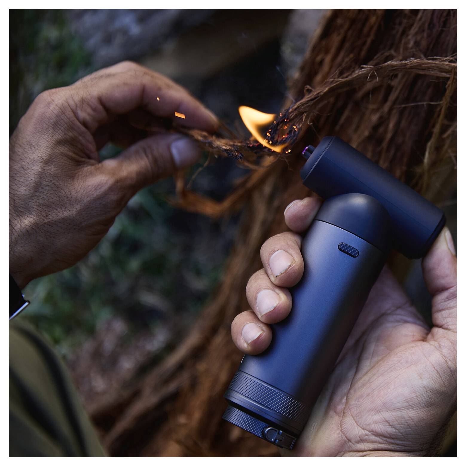 Eine Person verwendet ein tragbares elektrisches Haarstyling-Gerät, um eine kleine Haarpartie zu verbrennen, während sie die Strähne mit der anderen Hand hält.