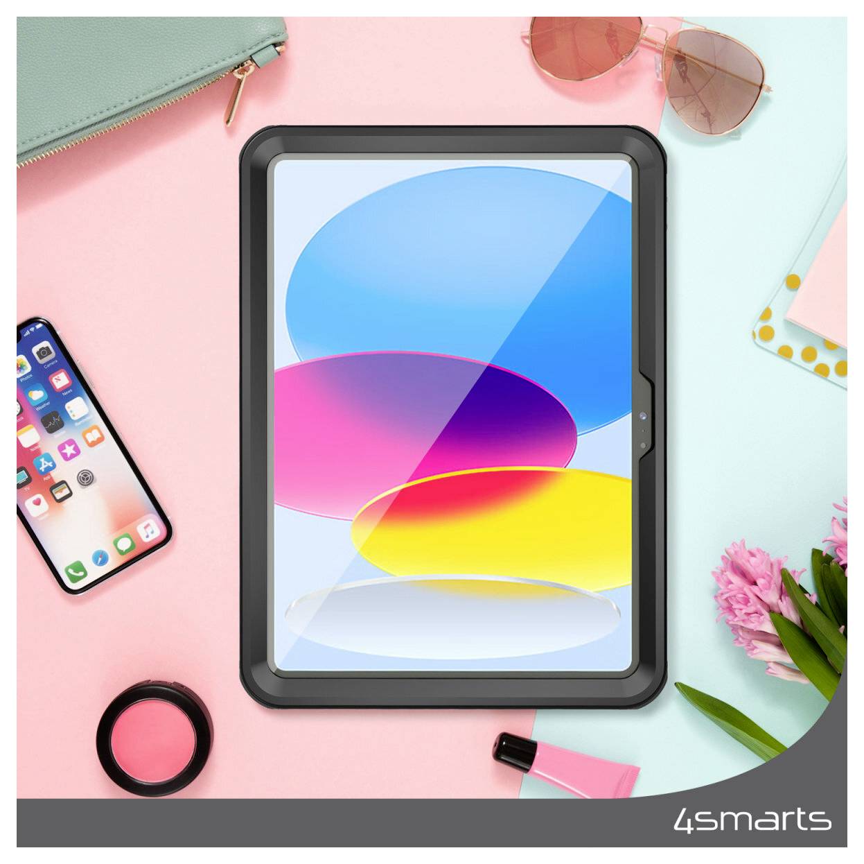 Ansicht von oben auf einen Schreibtisch mit einem Tablet, das bunte abstrakte Ovale zeigt, umgeben von einem Telefon, Sonnenbrille, Geldbörse, Make-up, Blumen und Schreibwaren auf einem pastellrosa und blauem Hintergrund.