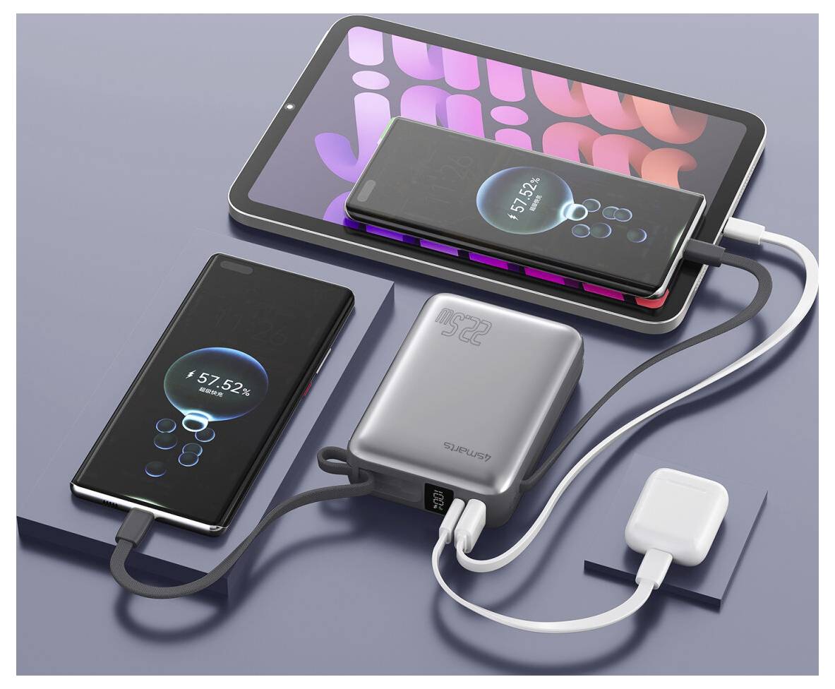 Mehrere Smartphones und ein Tablet werden von einer Powerbank aufgeladen, mit Kabeln, die mit einem Wandadapter auf einer grauen Oberfläche verbunden sind.
