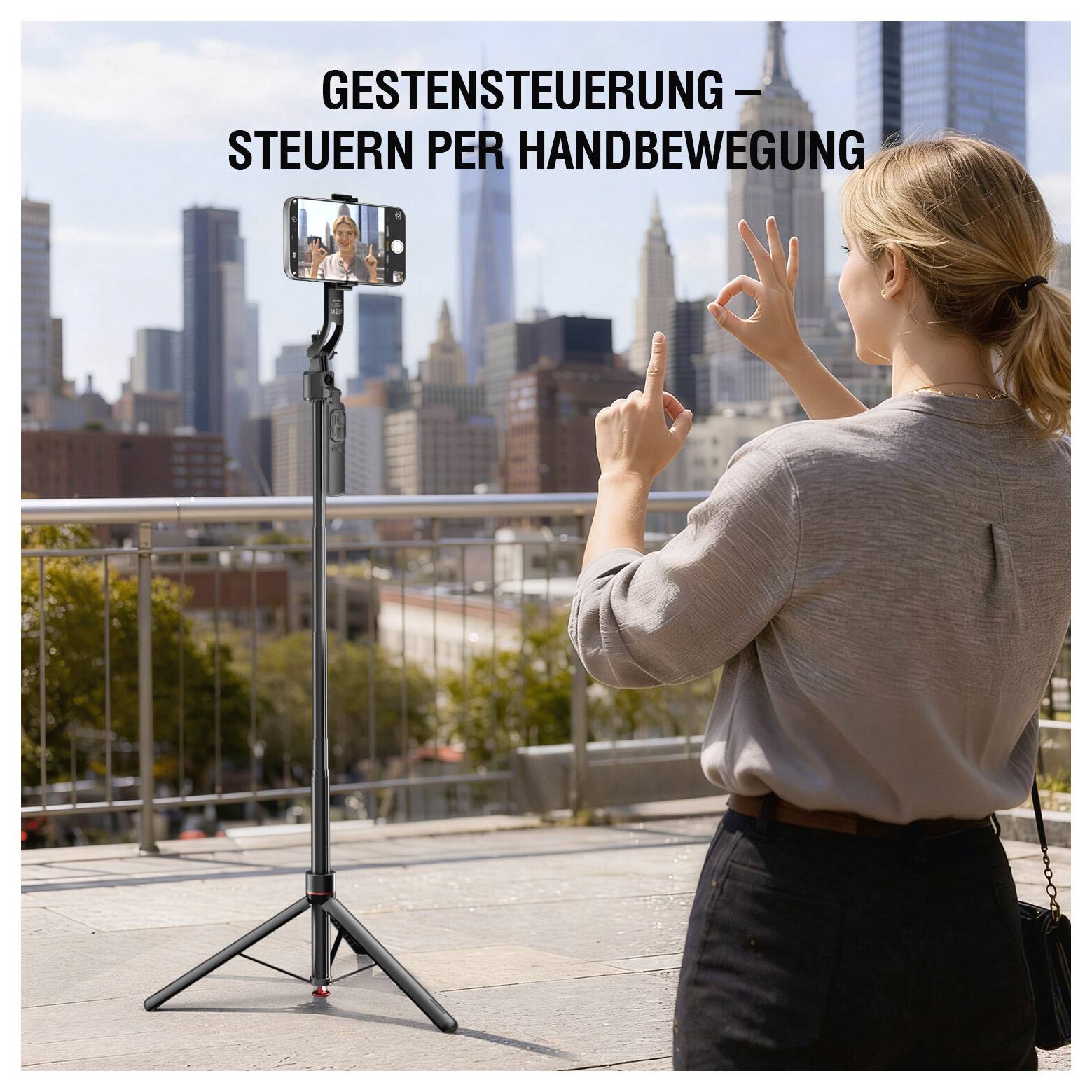 Frau, die Handgesten verwendet, um ein Smartphone auf einem Stativ zu steuern; deutscher Text lautet „GESTENSTEUERUNG – STEUERN PER HANDBEWEGUNG" vor einer Stadtsilhouette.