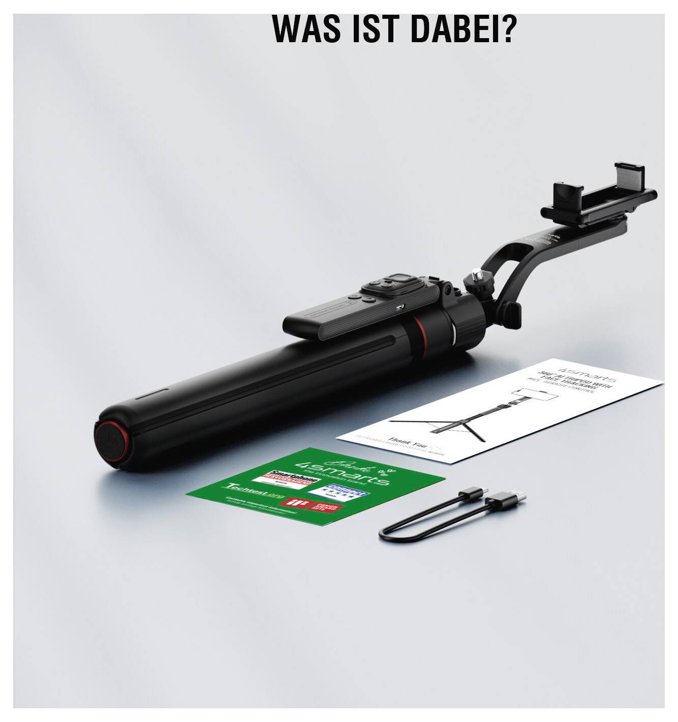 WAS IST DABEI?Produktfoto eines schwarzen Selfie-Sticks/Stativs mit Klemme, sowie enthaltene Bedienungsanleitungen/Karten und ein Kabel auf weißem Hintergrund unter der Überschrift „WAS IST DABEI?"