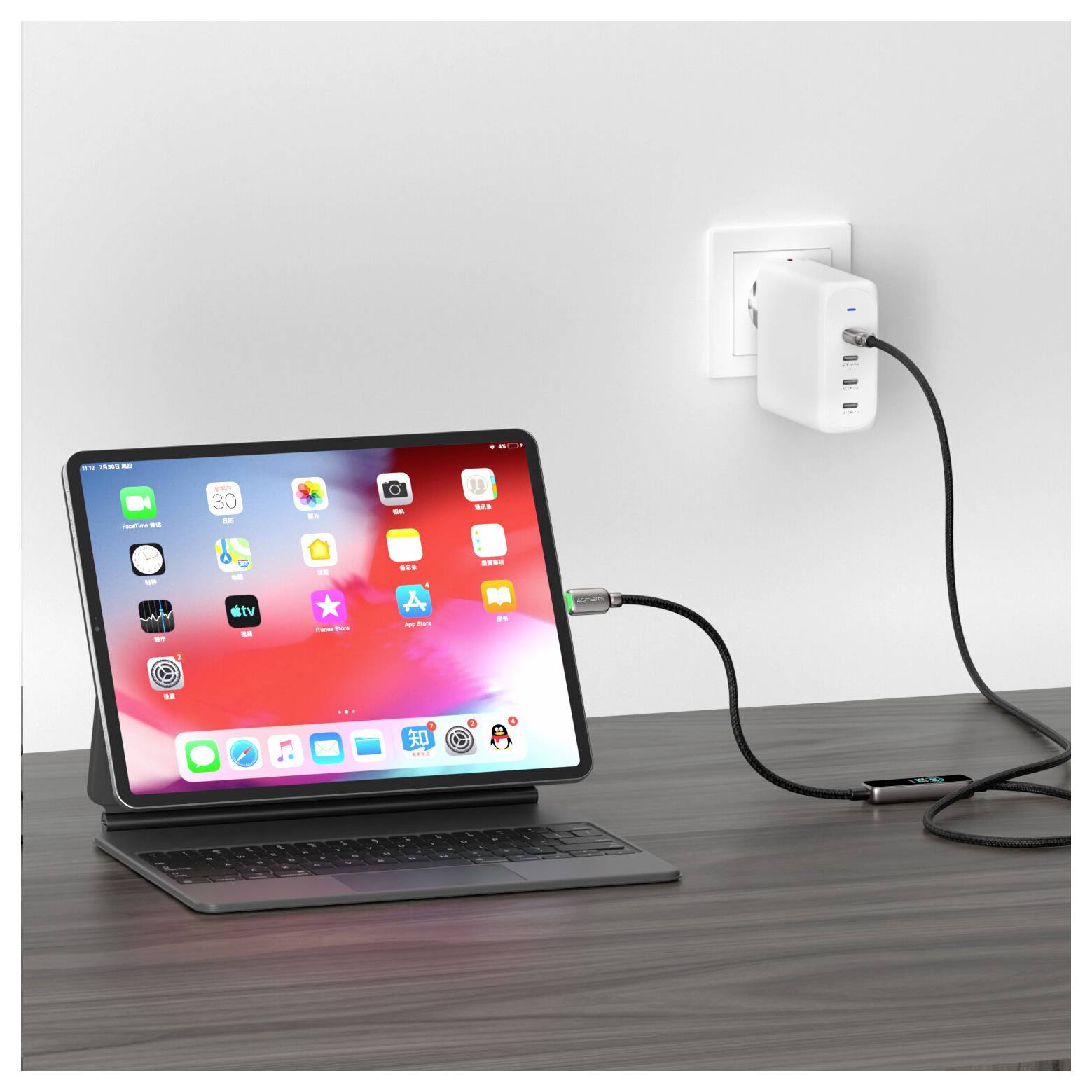 iPad auf einem Keyboard-Ständer, das über ein Kabel und einen Stromanschlussadapter aus einer Wandsteckdose auf einem Schreibtisch aufgeladen wird.